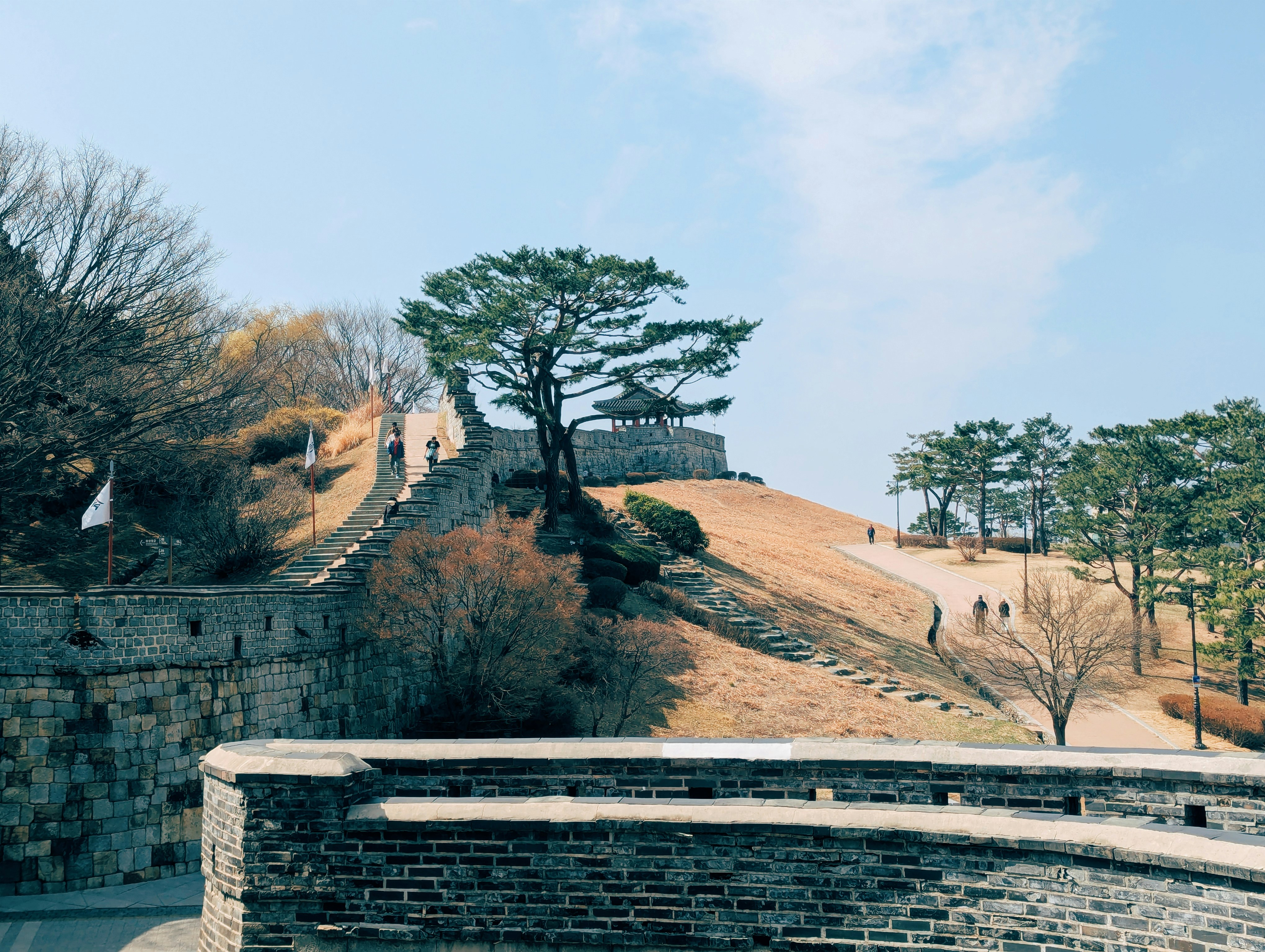 Ancient stone fortress wall with a watchtower and trees.