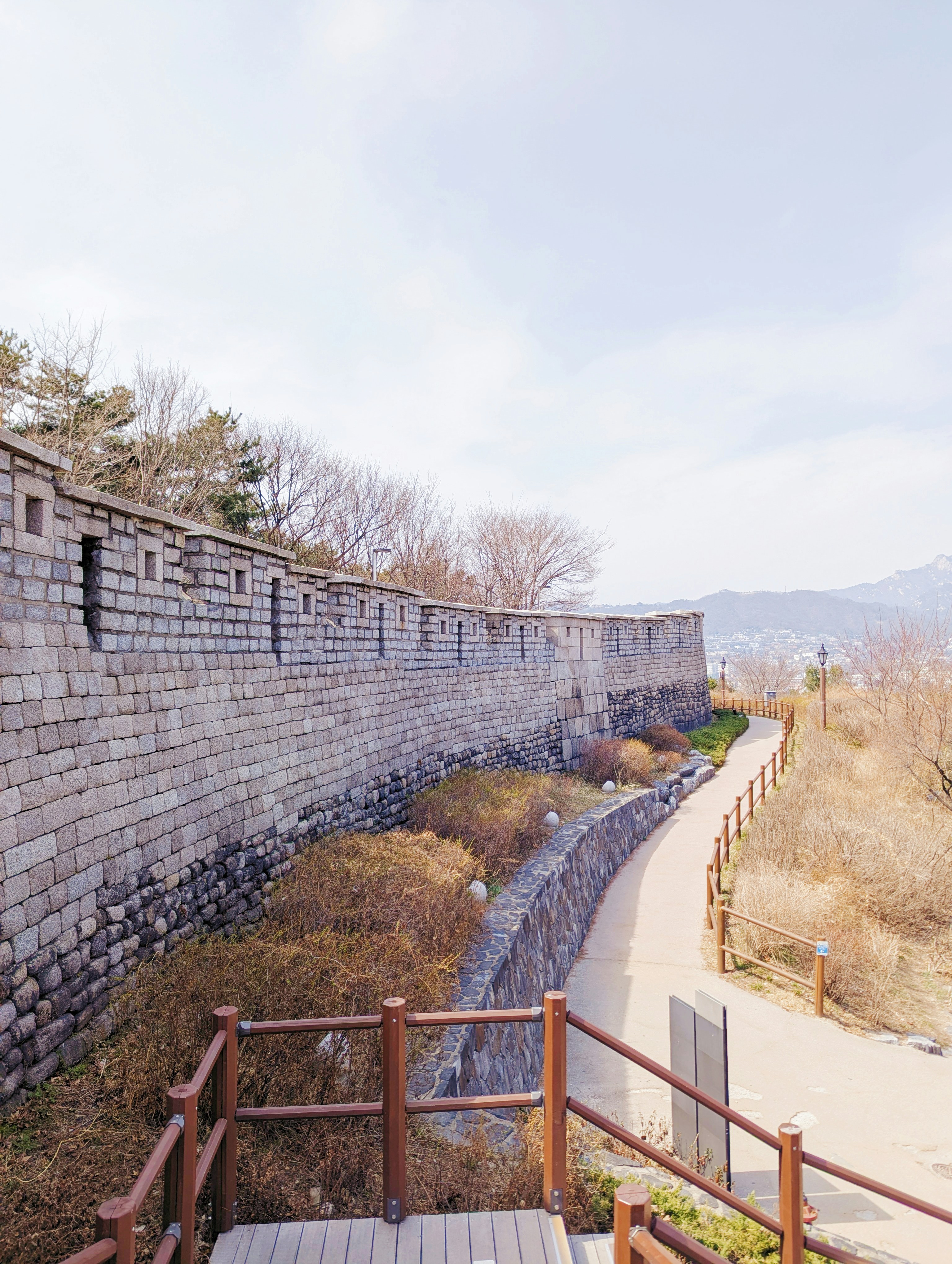 Stone fortress wall with a pathway and wooden railings