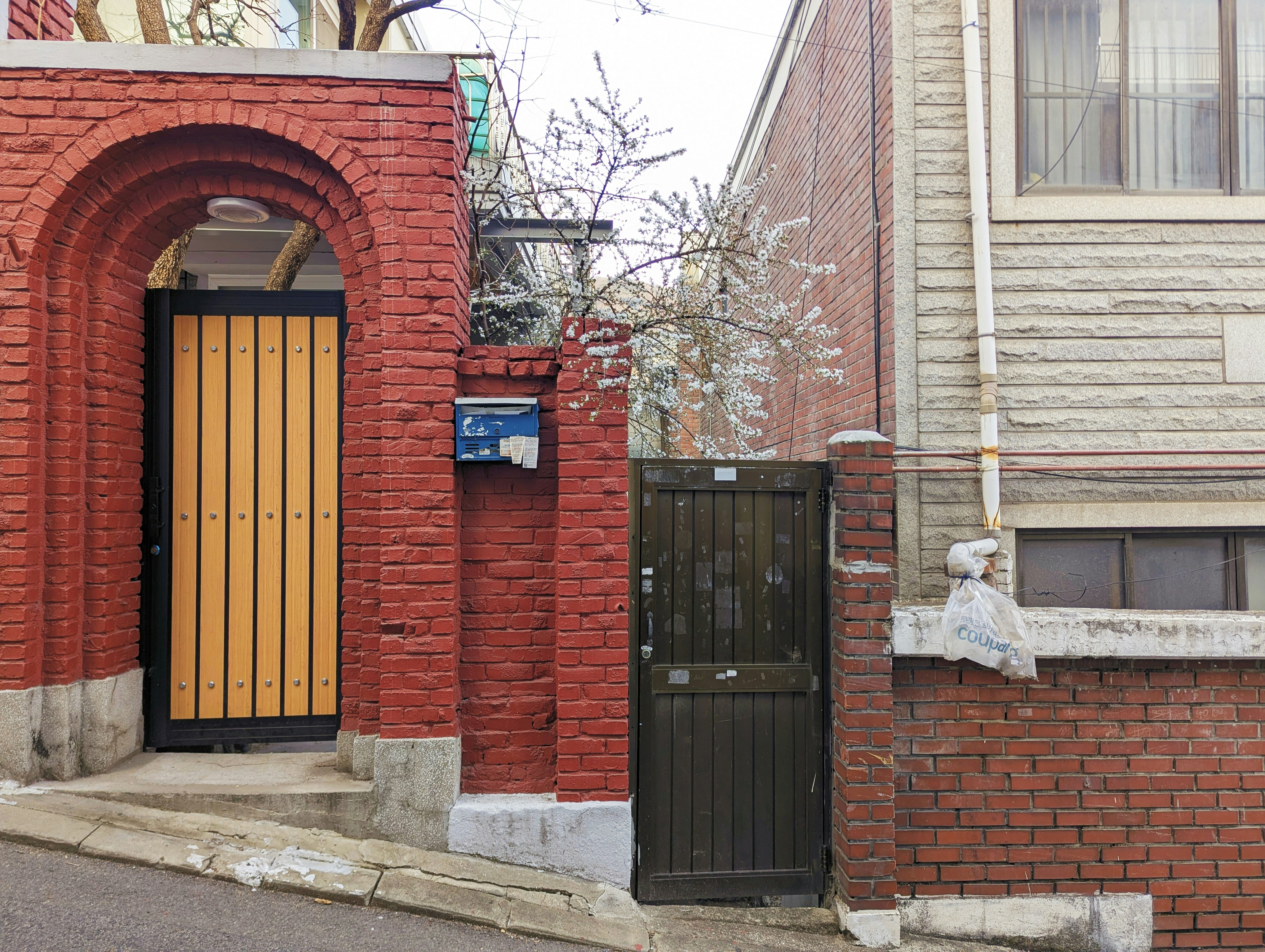 Red brick wall with two different doors and archway.