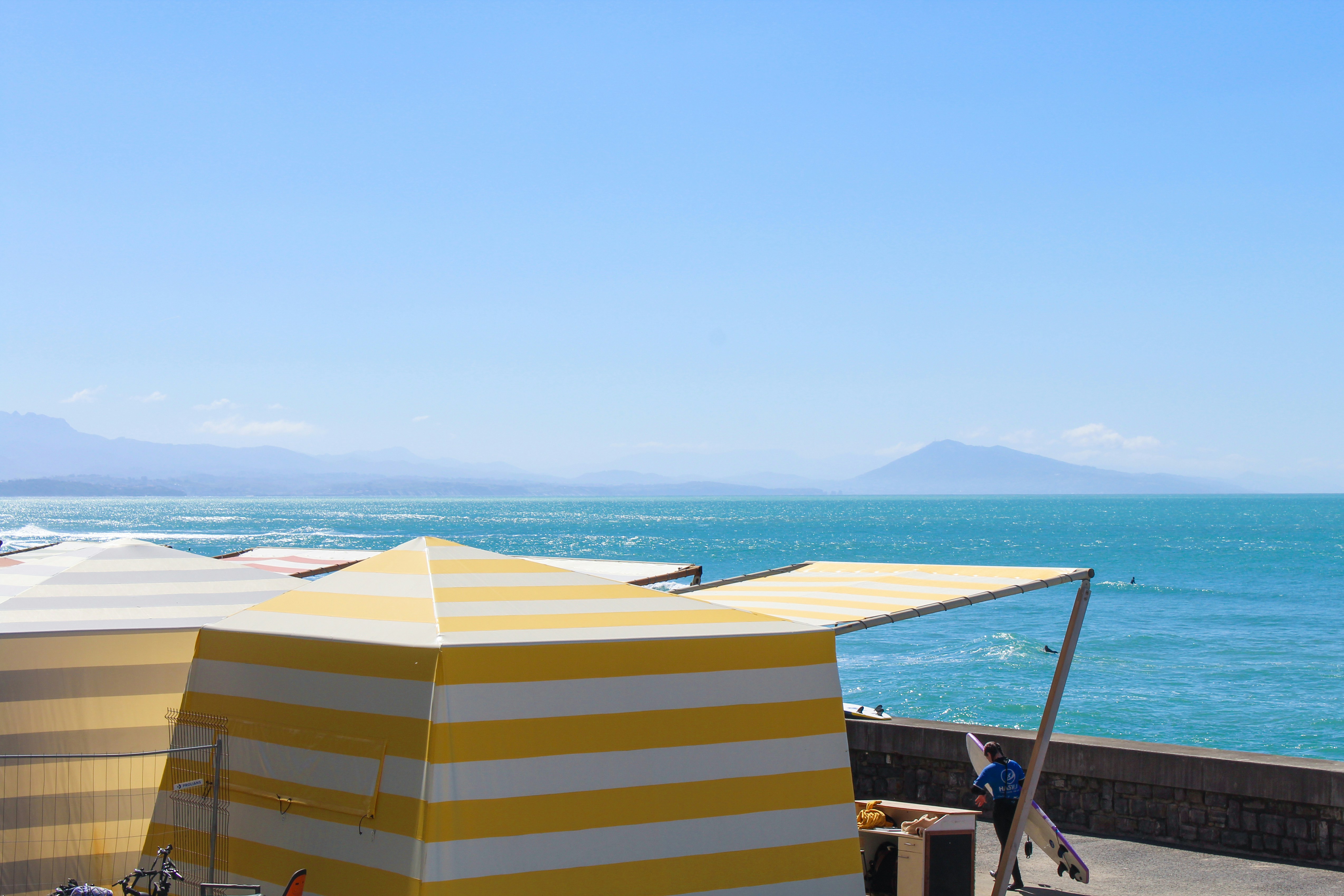 Tenda pantai dan lautan di bawah langit biru yang cerah