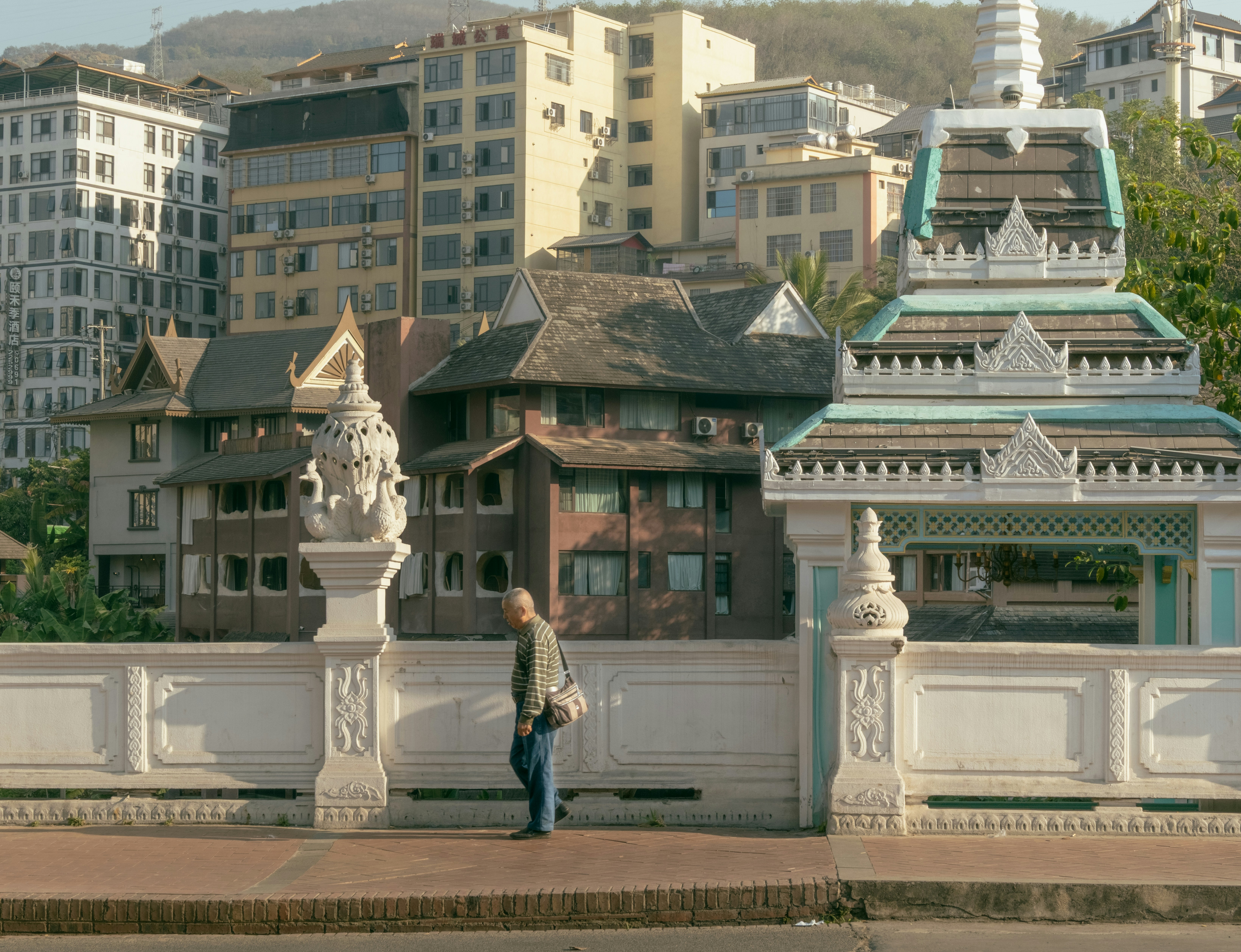 Man walks on a bridge with buildings in background