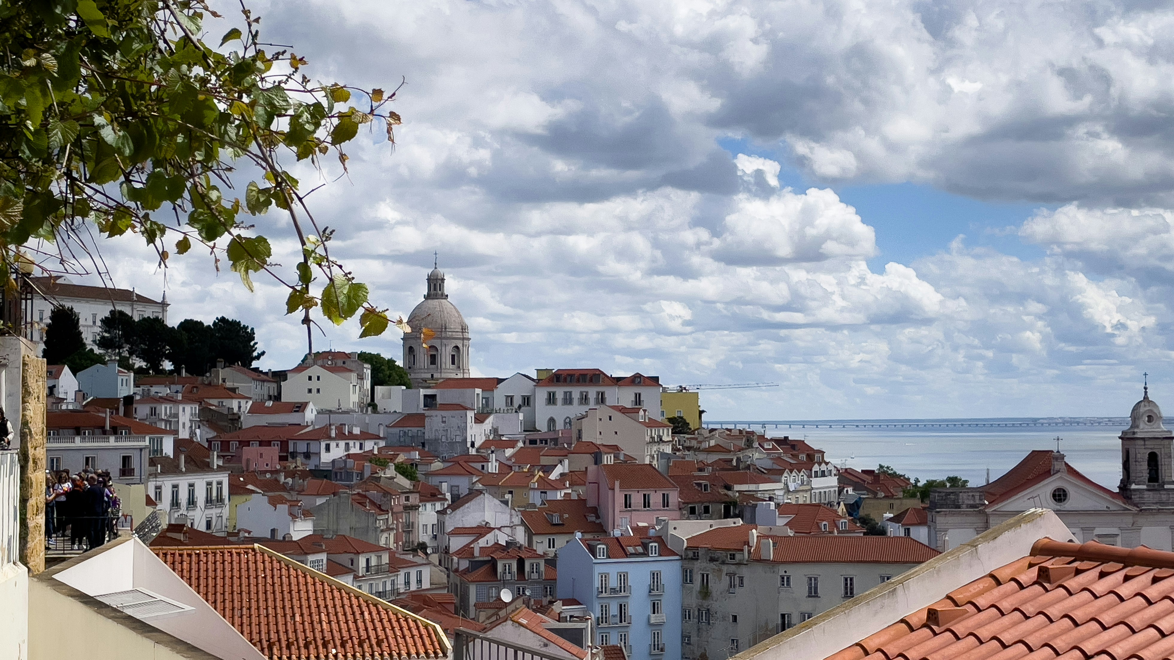View of lisbon cityscape with tiled roofs and ocean.