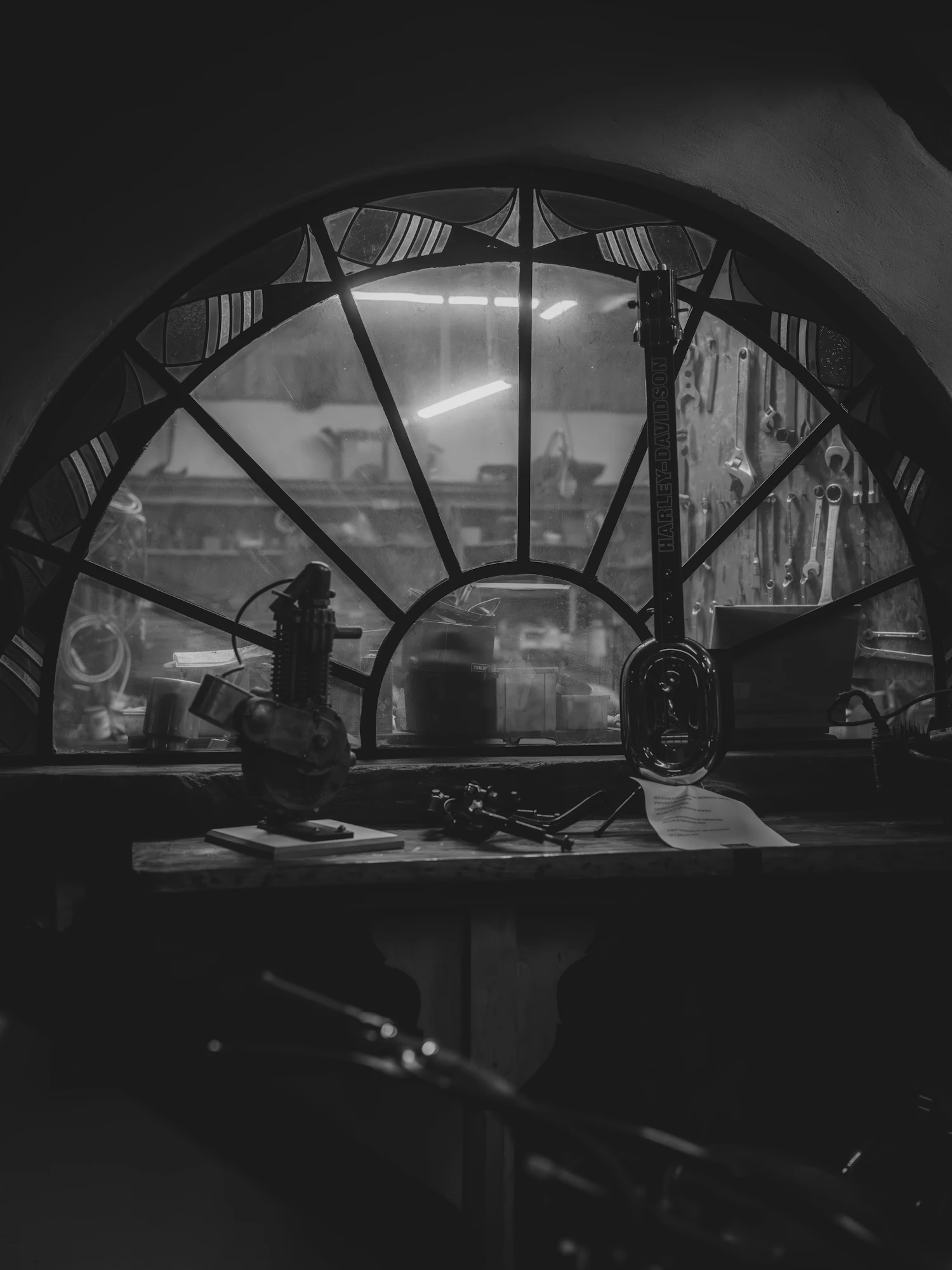 An arched workshop window seen from inside, instruments laid out on the sill