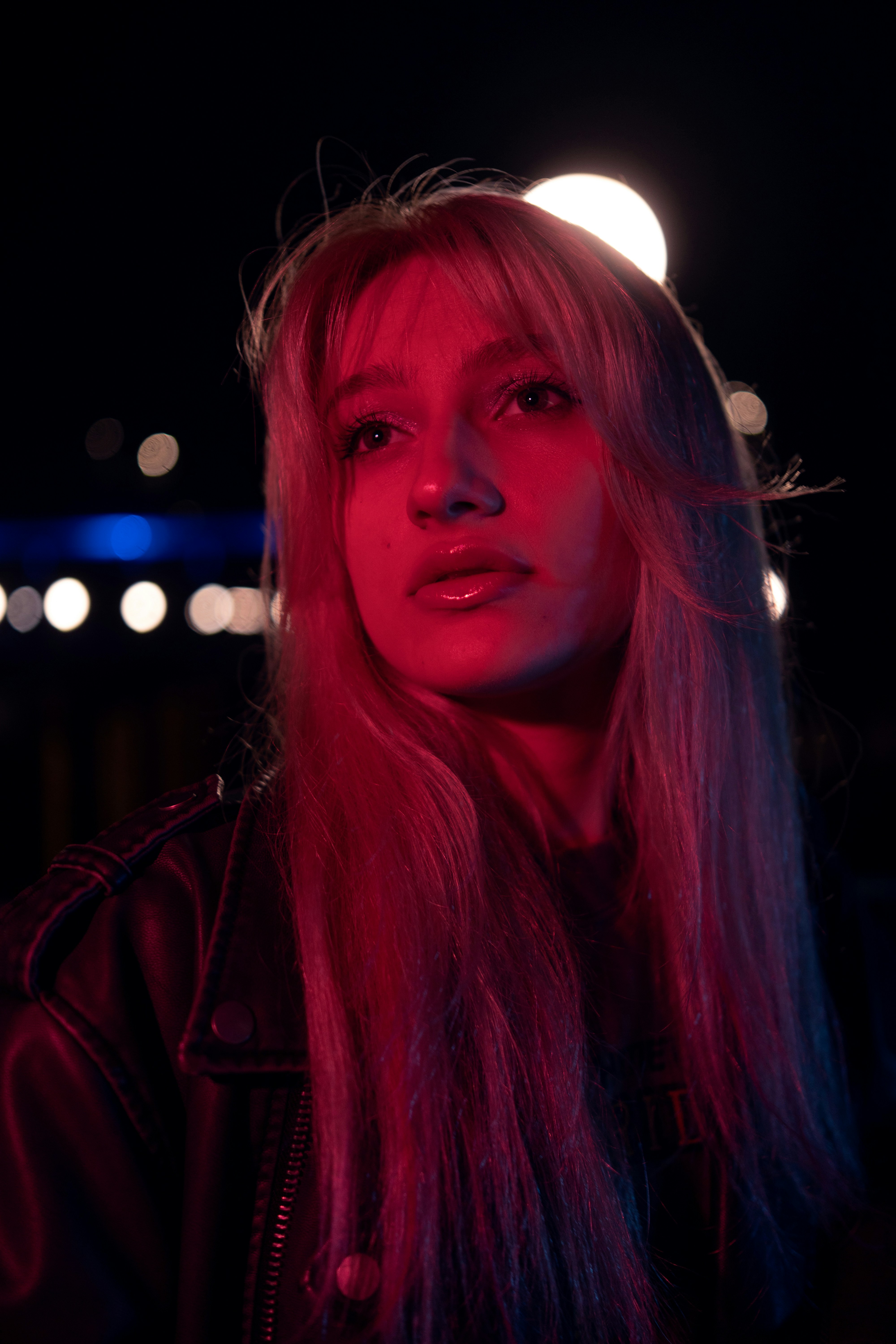 Young woman illuminated by pink and blue neon lights.