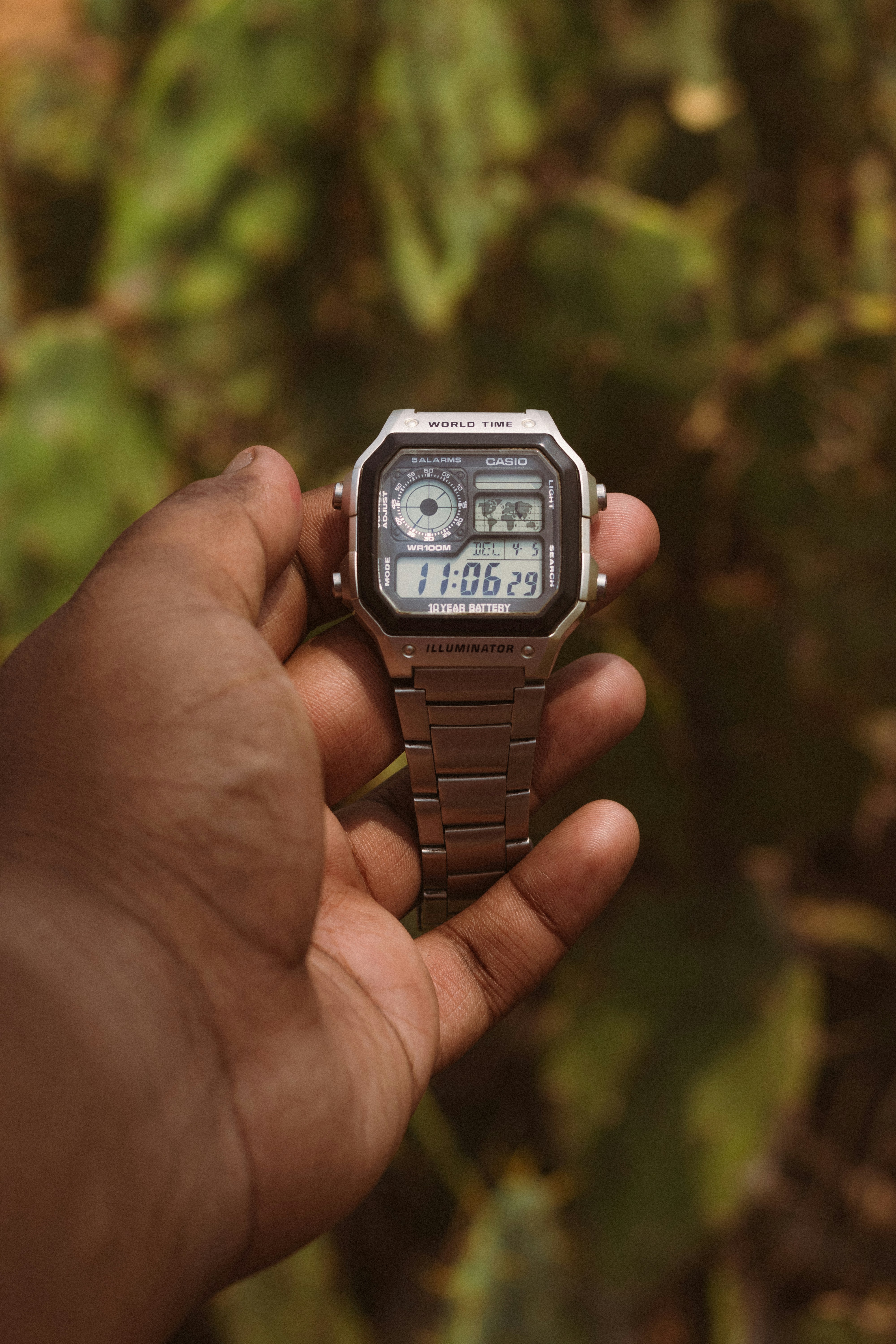 Hand holding a digital watch with cactus background