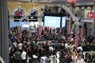 Crowd gathered at an indoor event with a large screen.