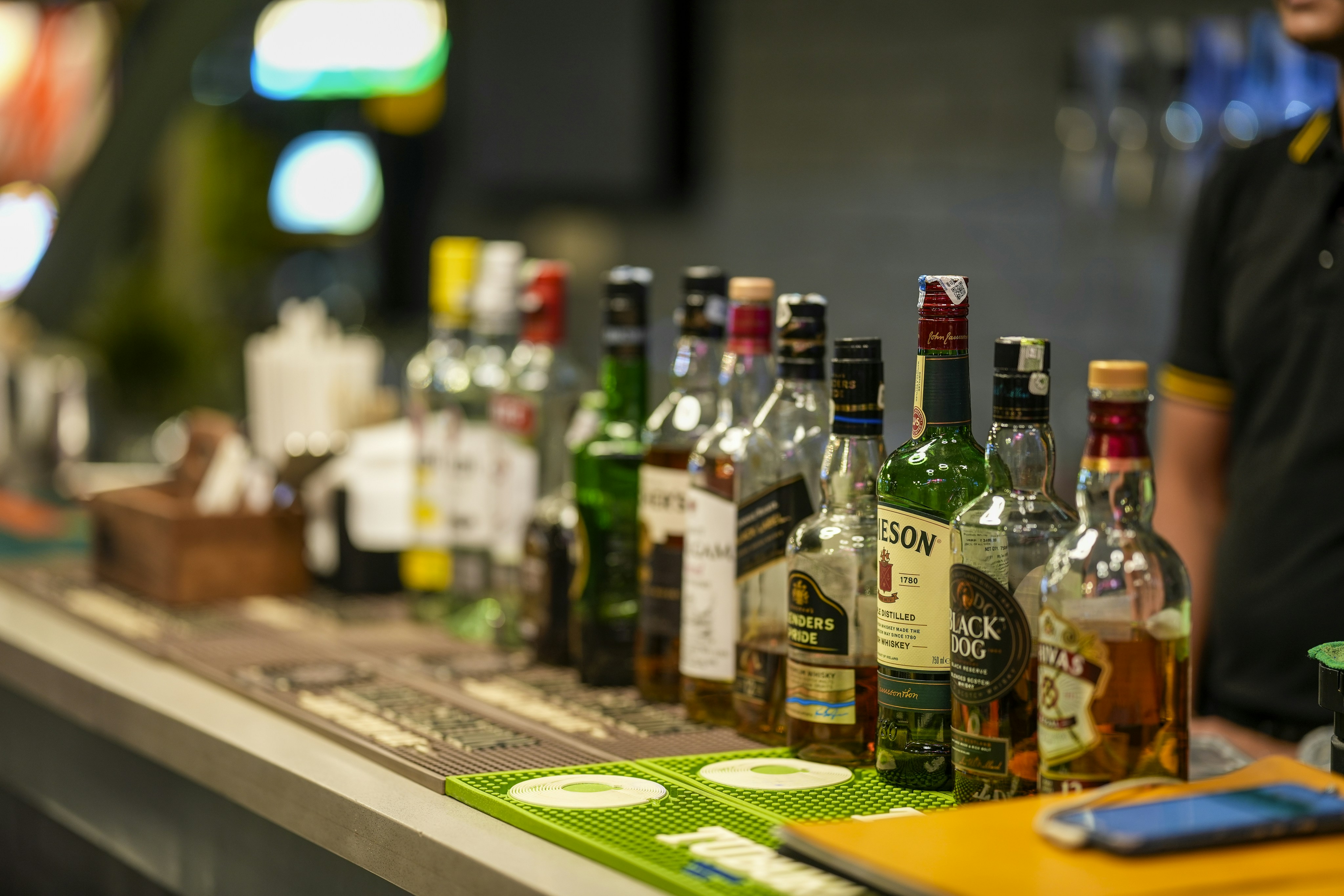 Bottles of alcohol lined up on a bar counter.