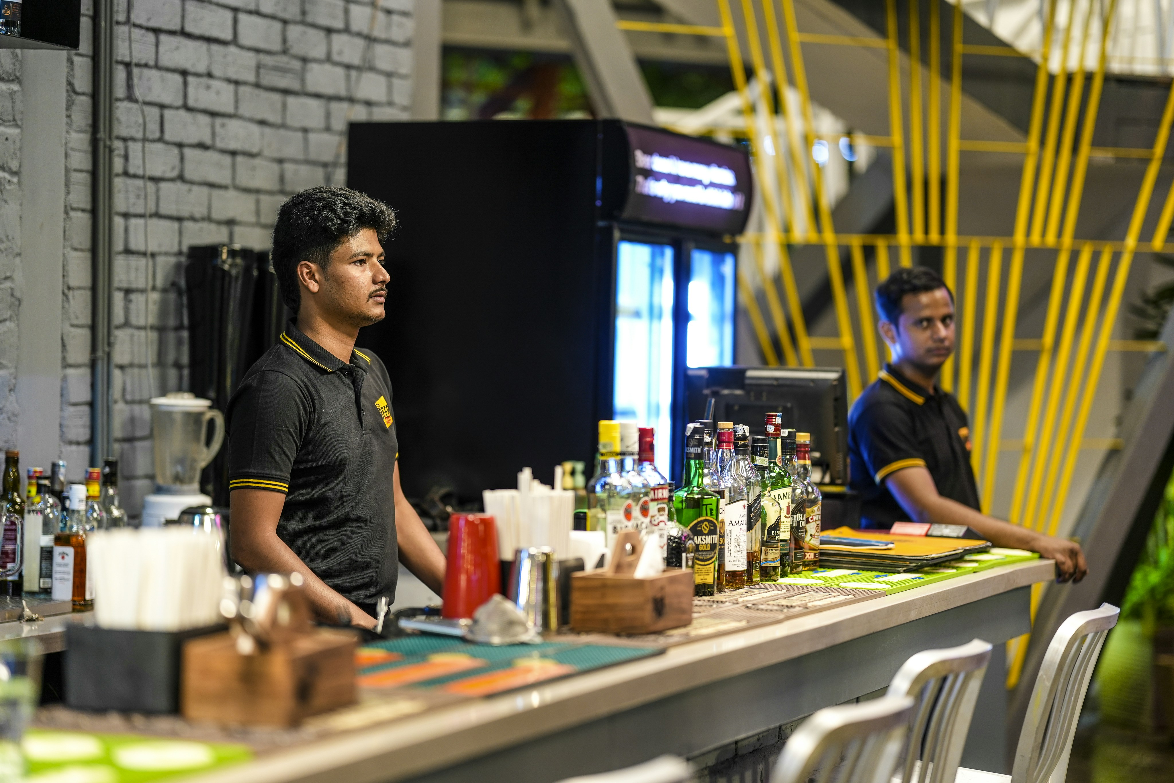 Bartenders working behind a bar with bottles