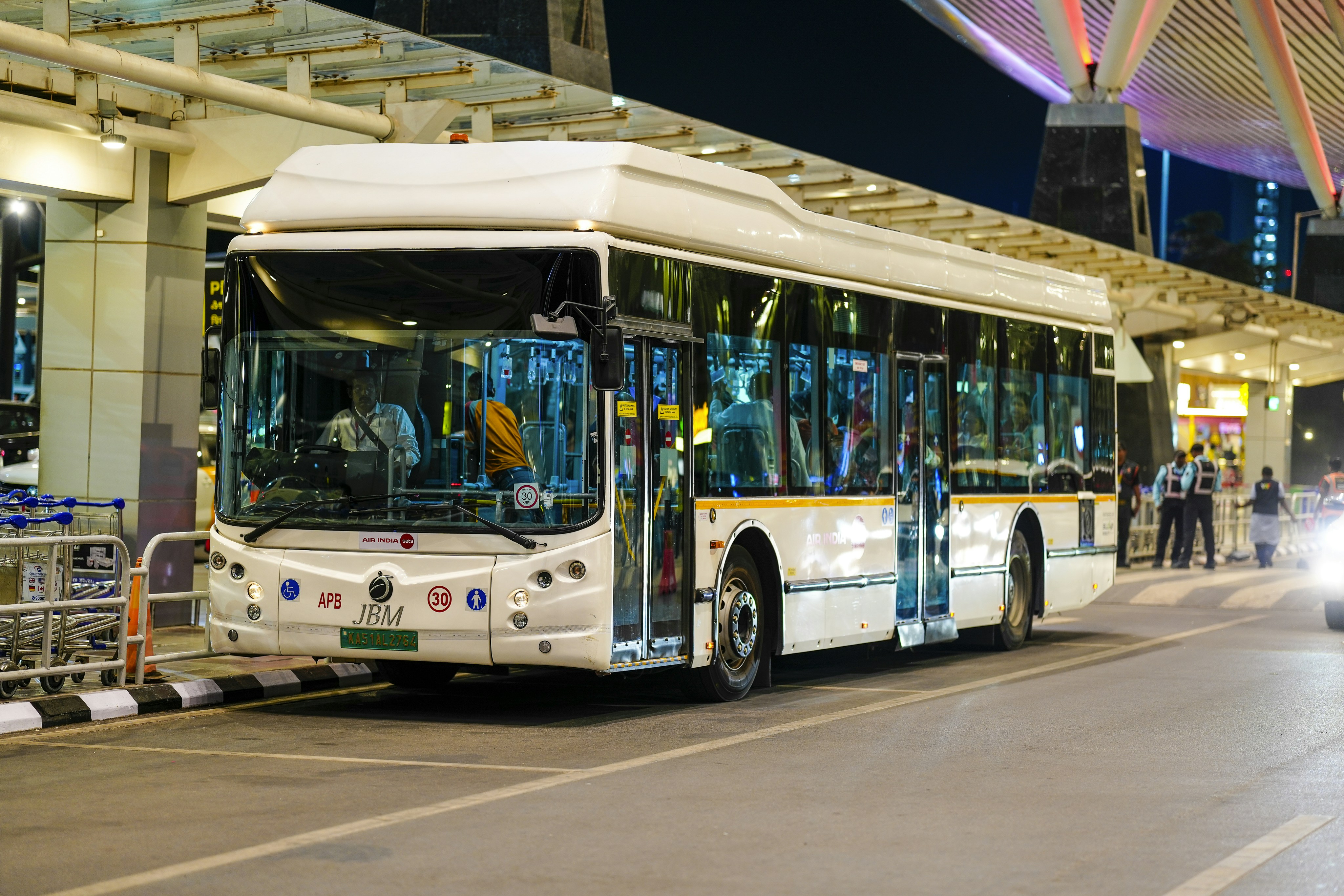 A white bus parked at a terminal at night.