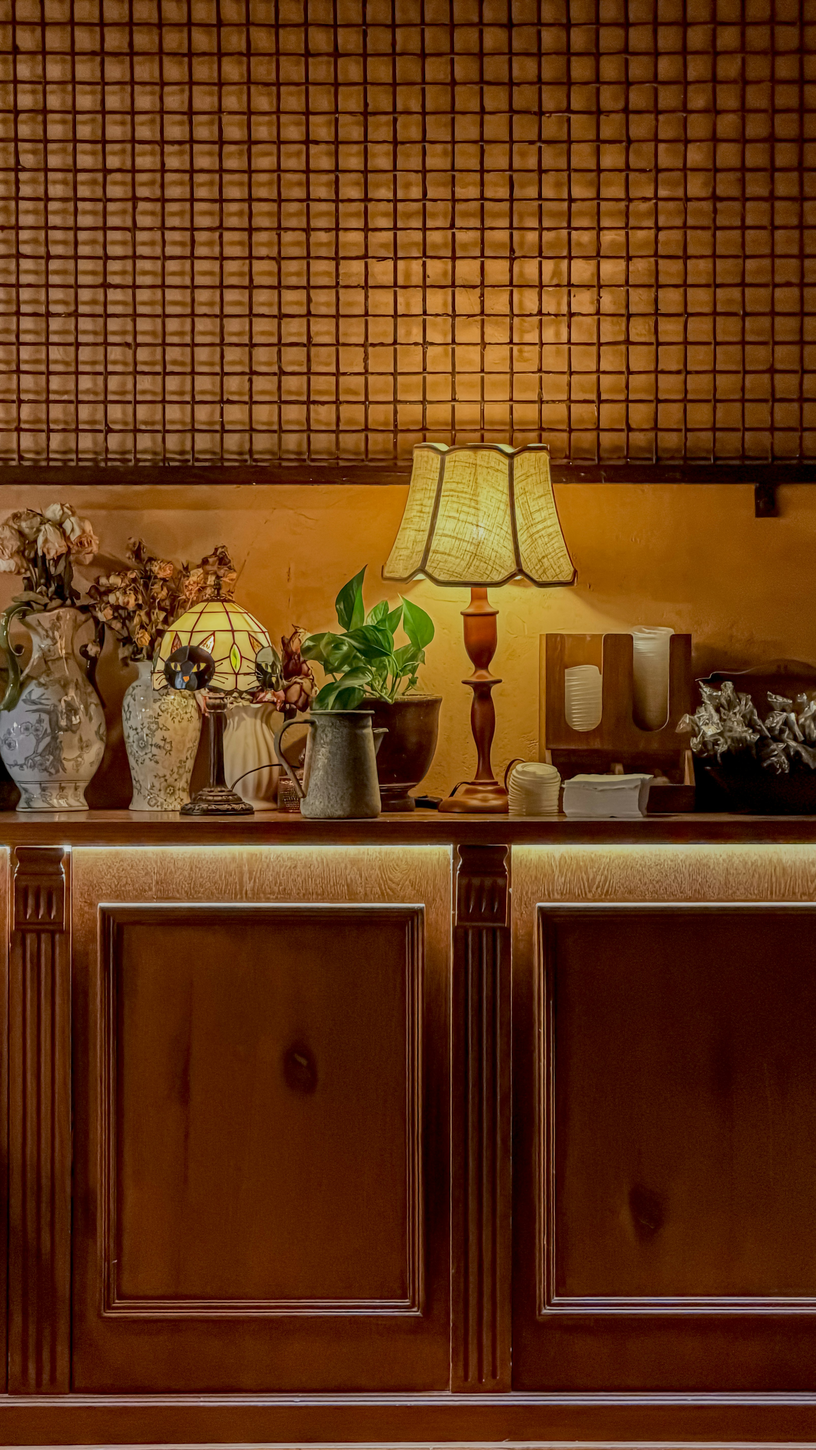 A dimly lit counter with decorative items and a lamp.