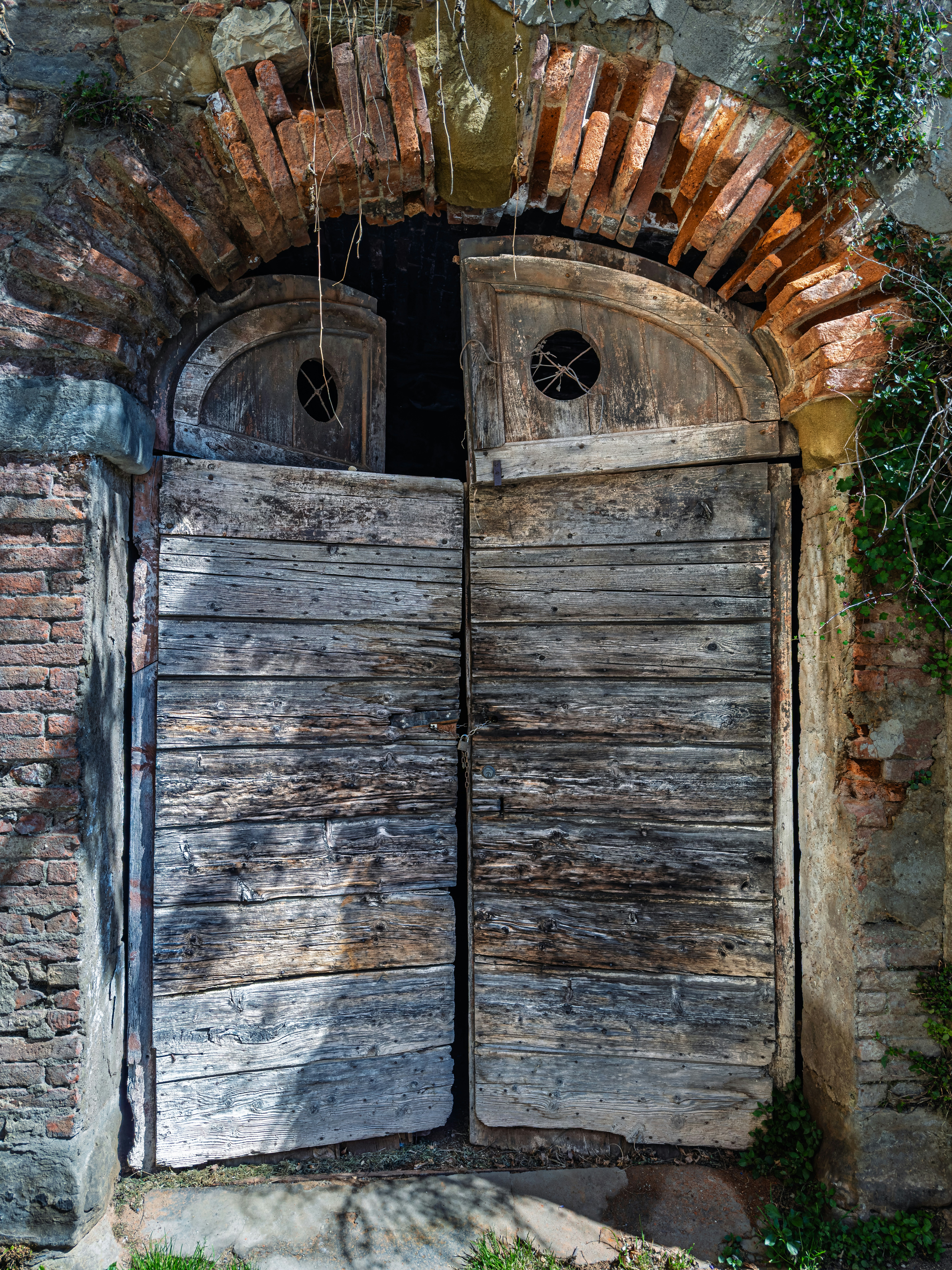 Old weathered wooden doors set in a brick archway.
