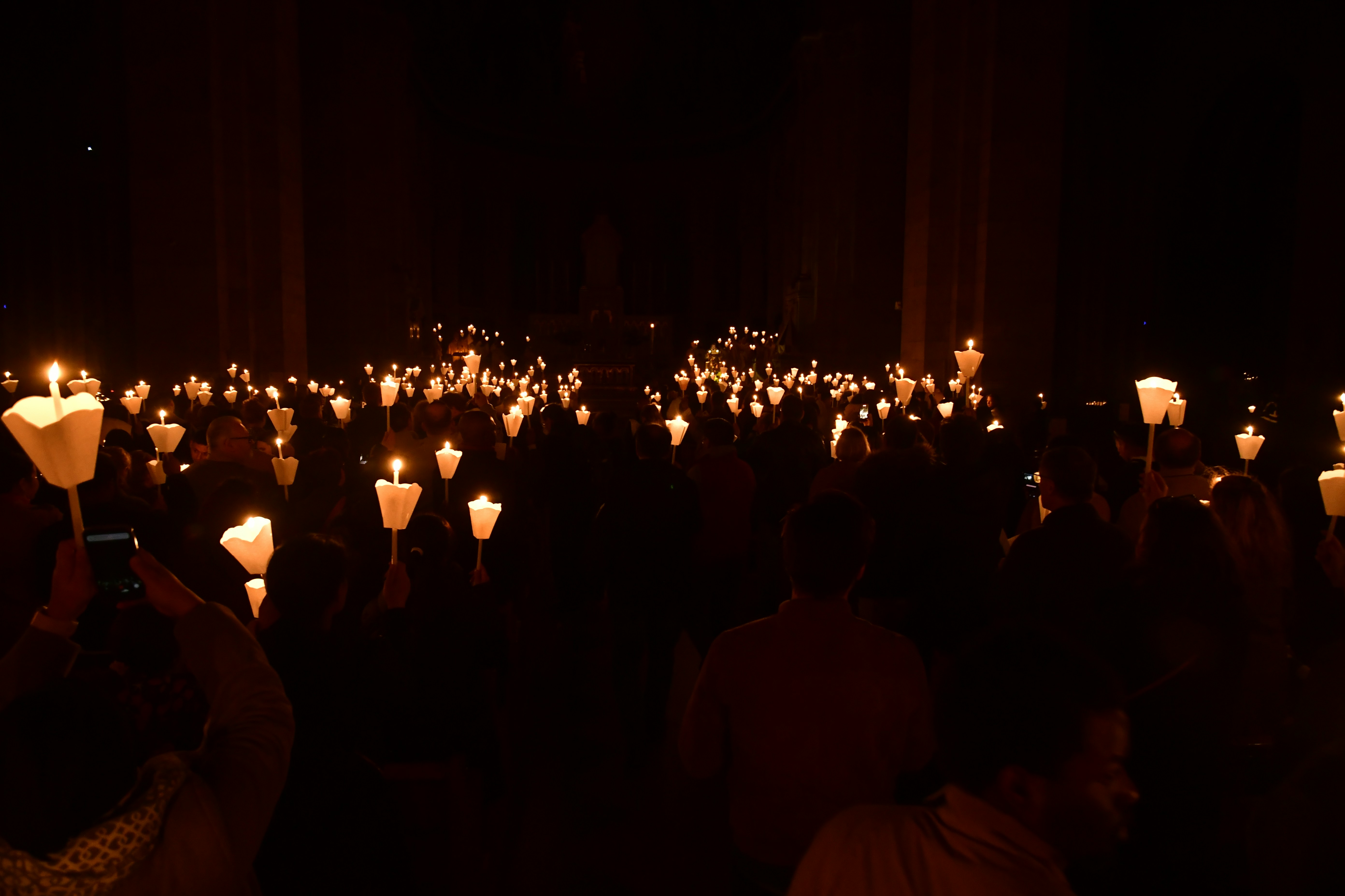 A crowd holding candles in the dark