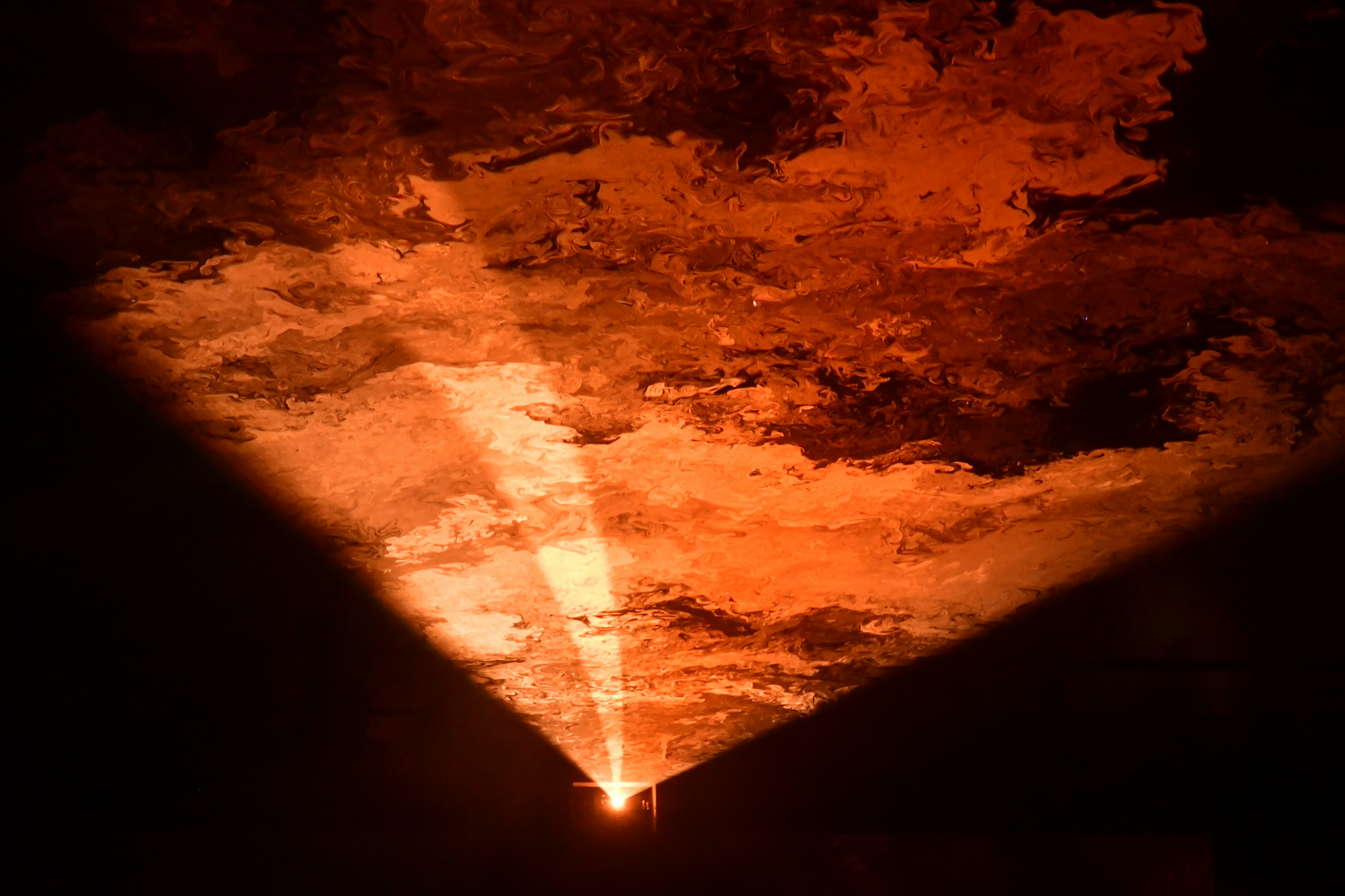 A beam of light shines through fiery clouds