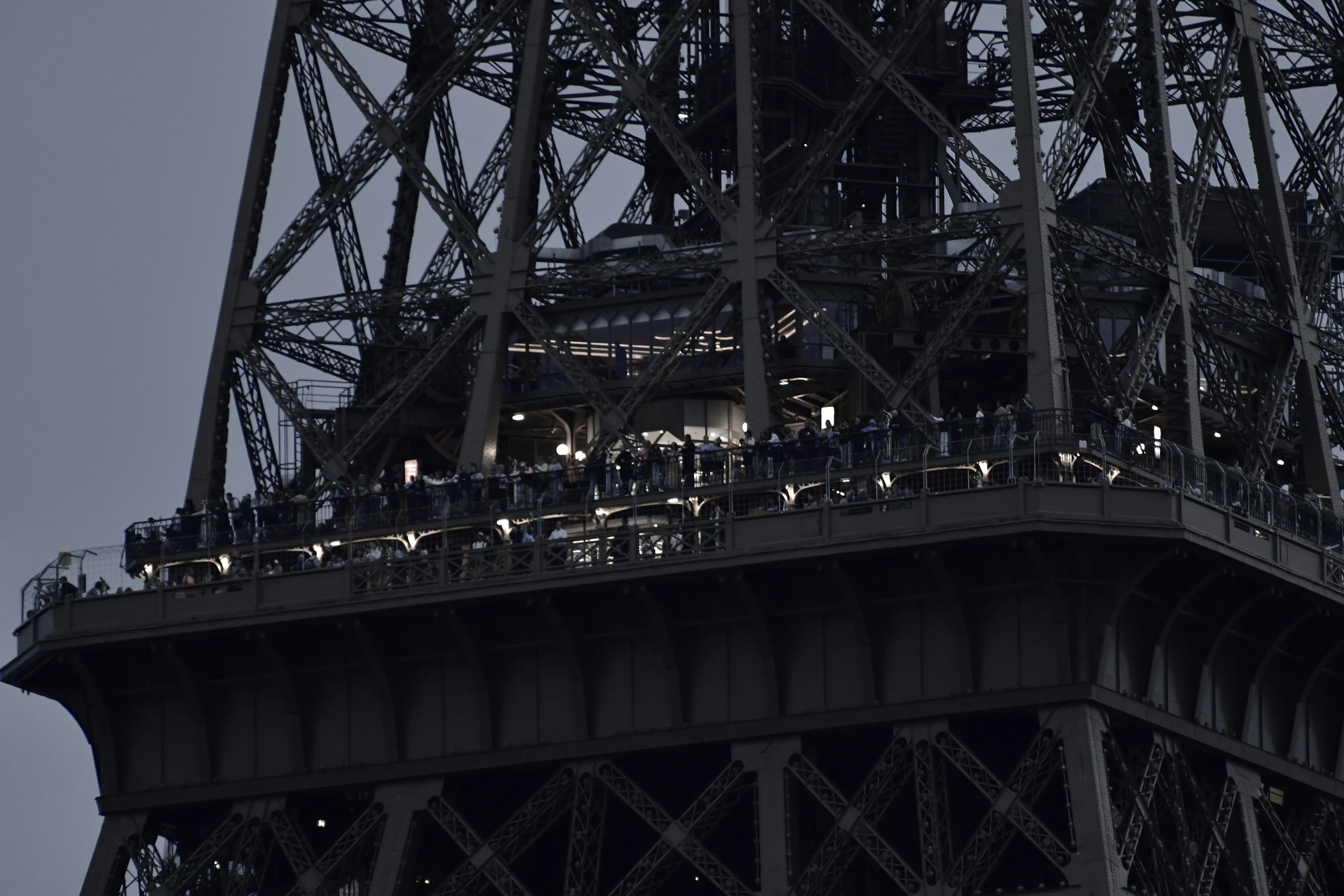 Close-up of the eiffel tower with many people visible.