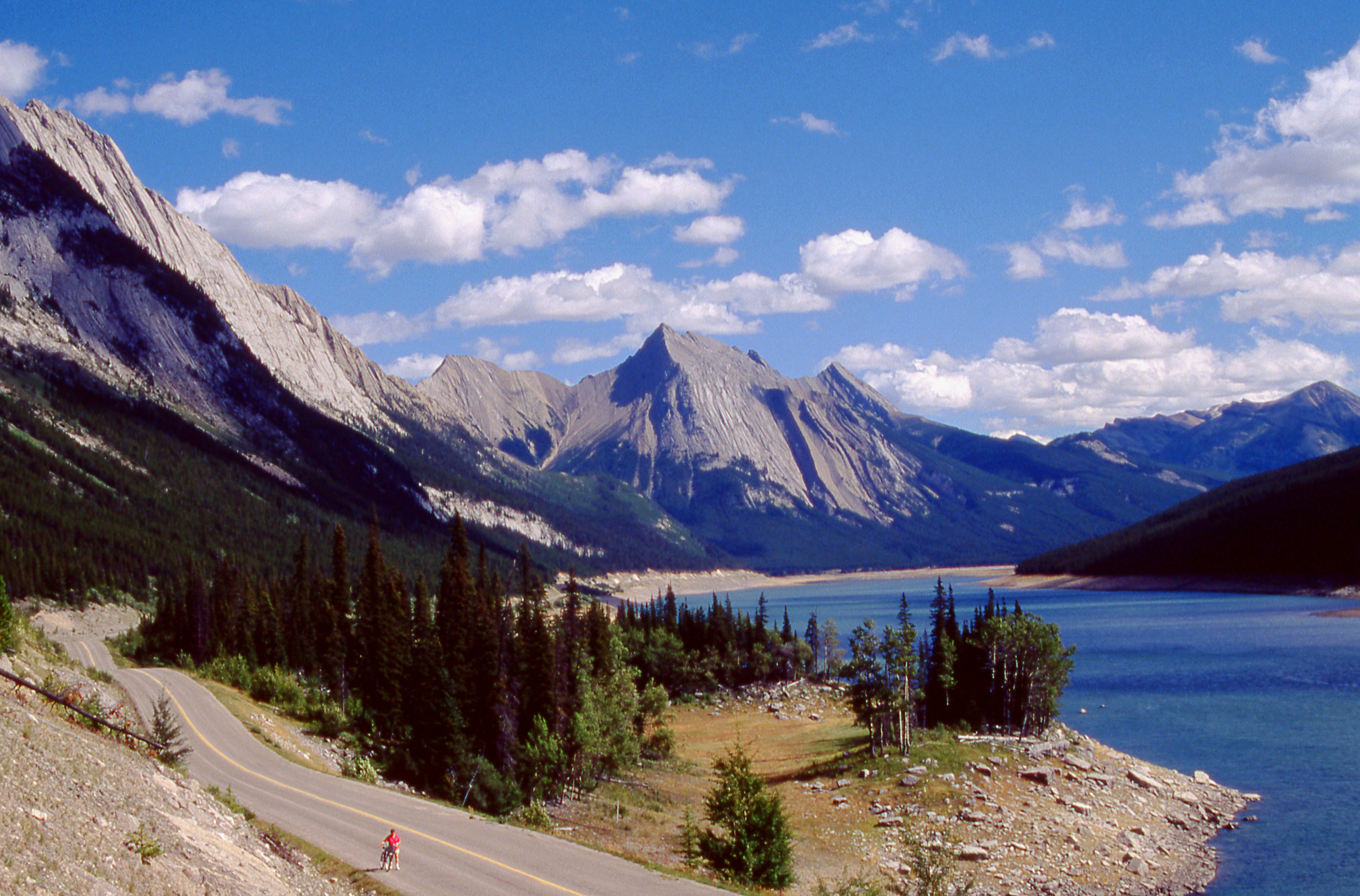 Winding road beside a blue lake and mountains