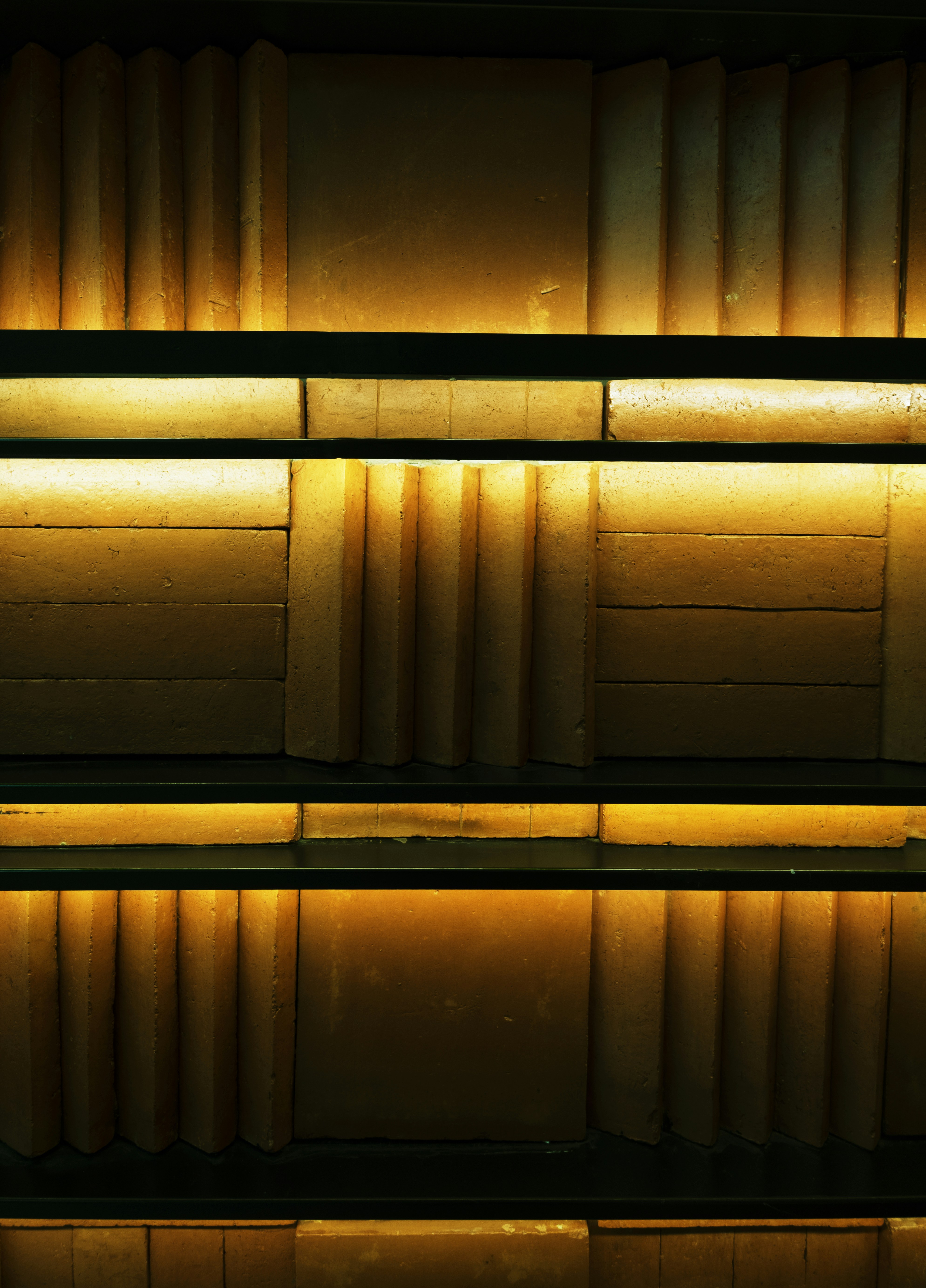 Rows of yellow cheese illuminated by warm lights