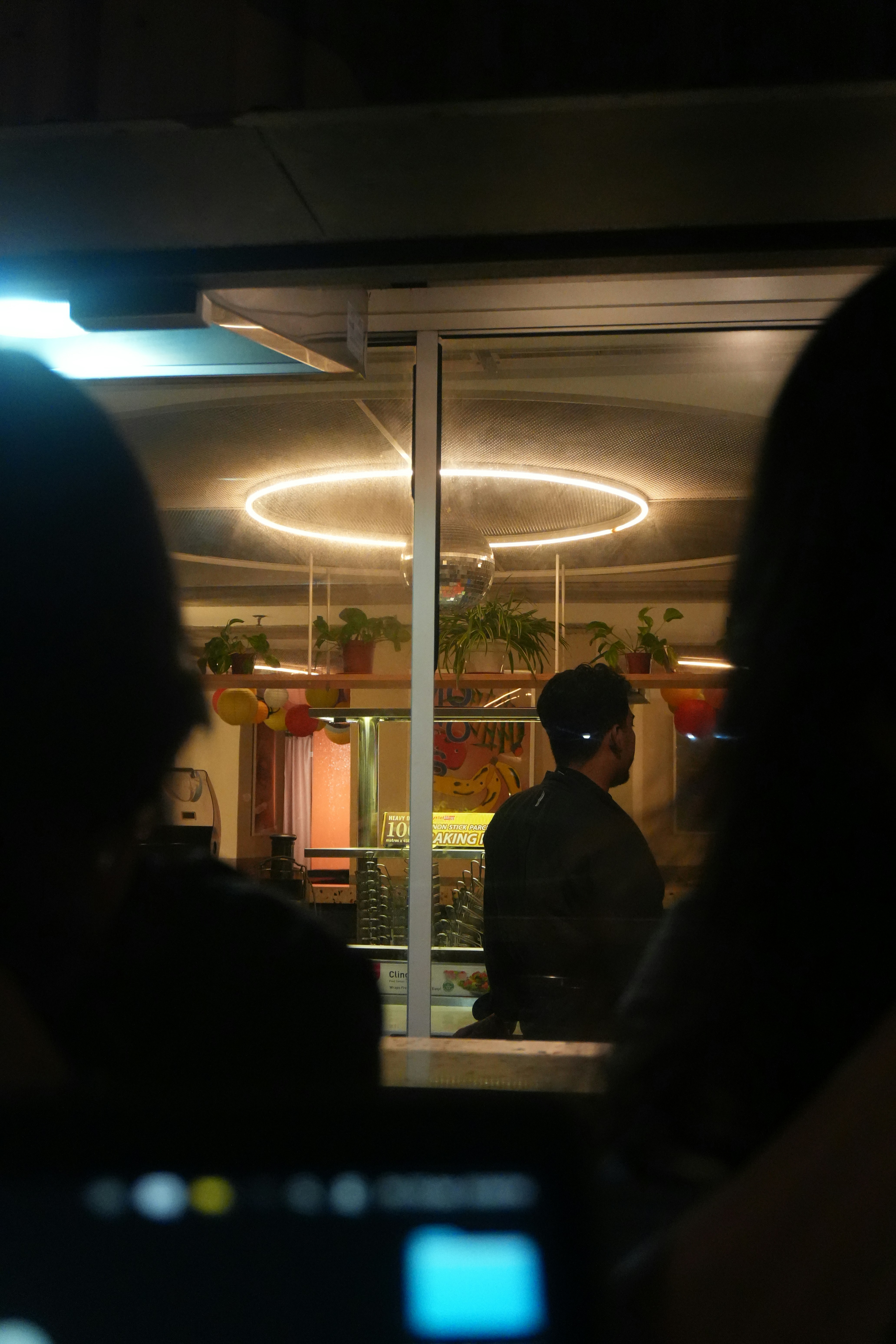 밝게 불이 켜진 밤의 카페 안에 있는 사람들