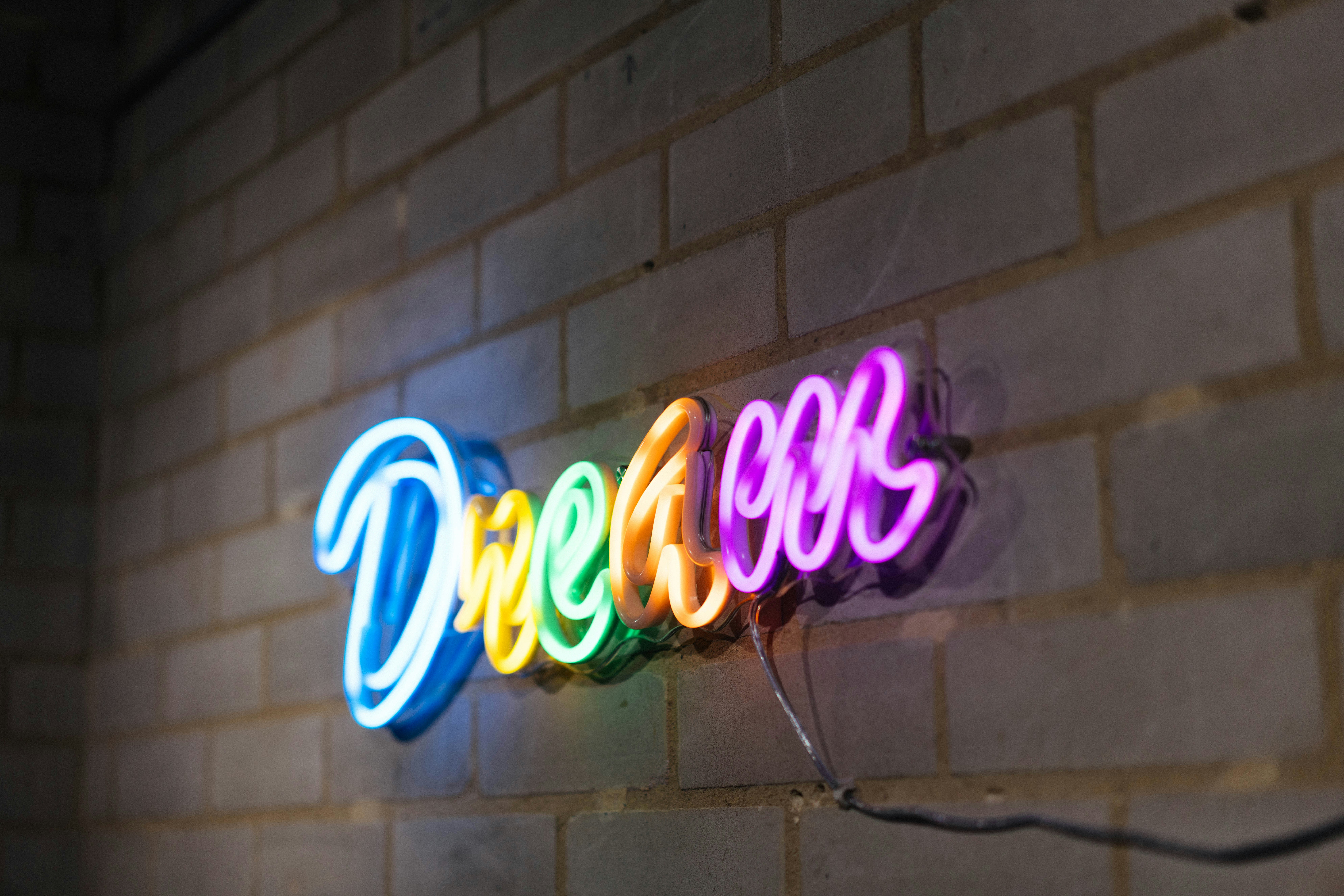 レンガの壁に「dream」と書かれたカラフルなネオンサイン