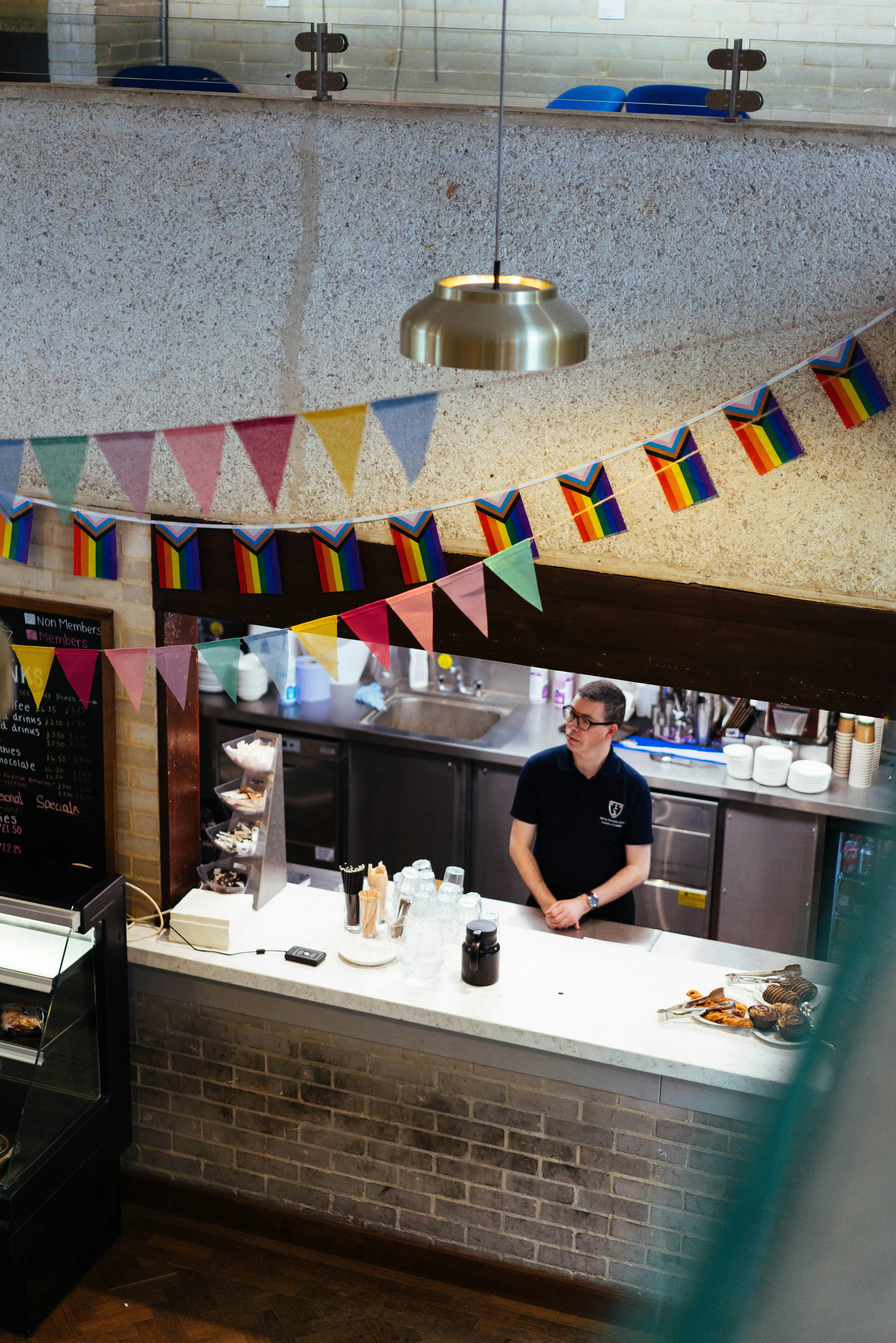 虹色の旗で飾られたカウンターの後ろに立つ男性。
