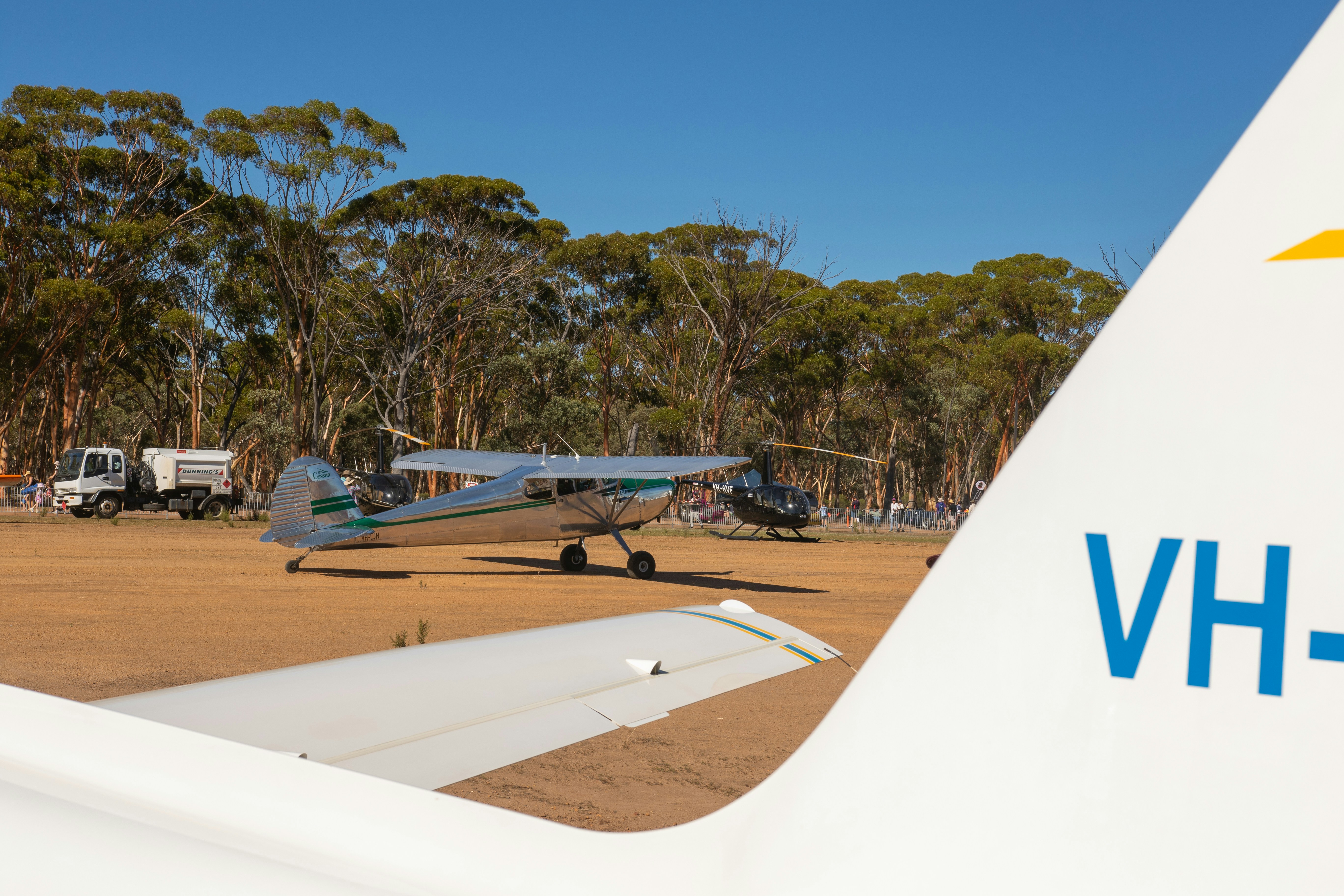 Small airplanes on a grassy airfield with trees