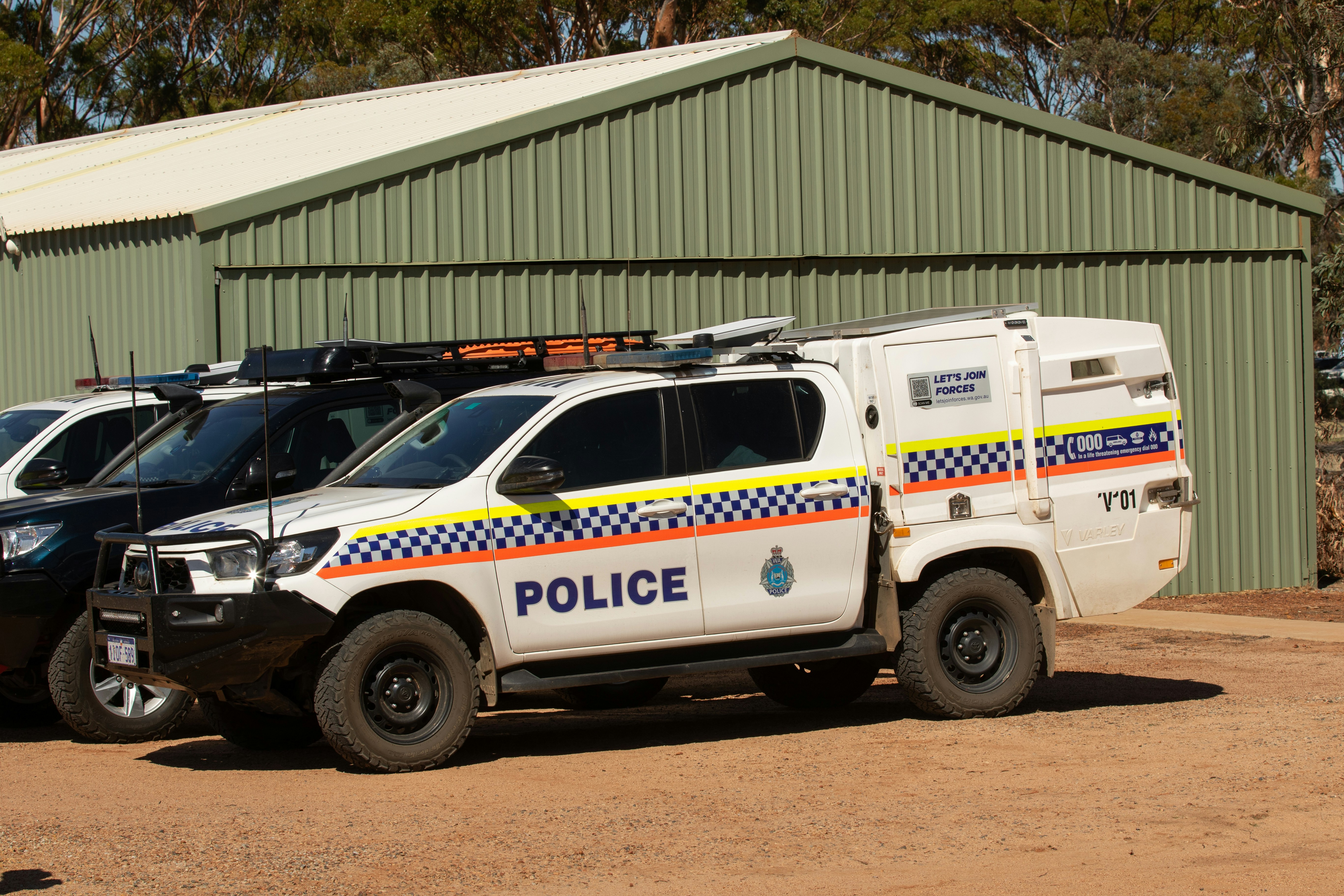 Police vehicles parked outside a green building.