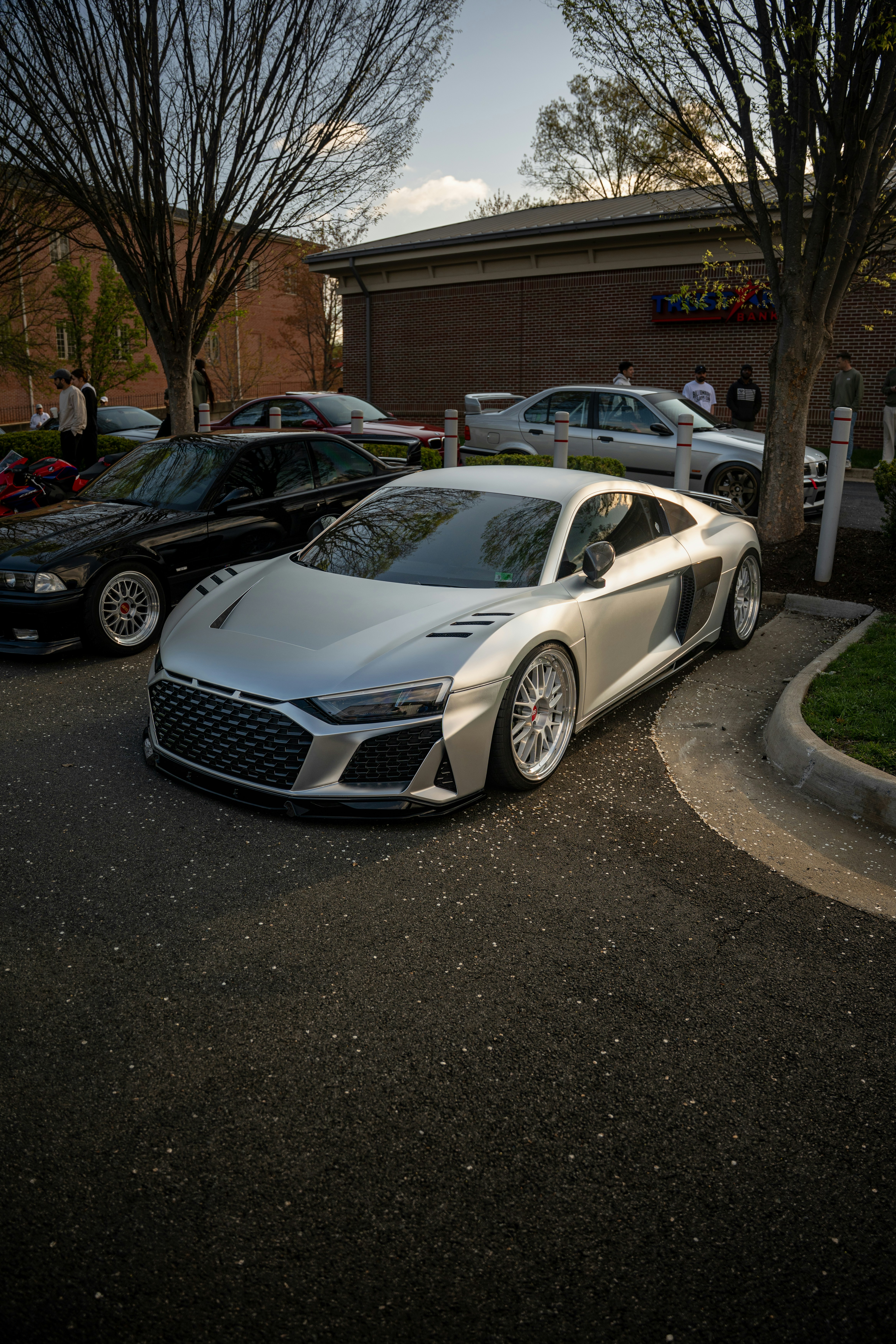 Silver sports car parked outside with trees.