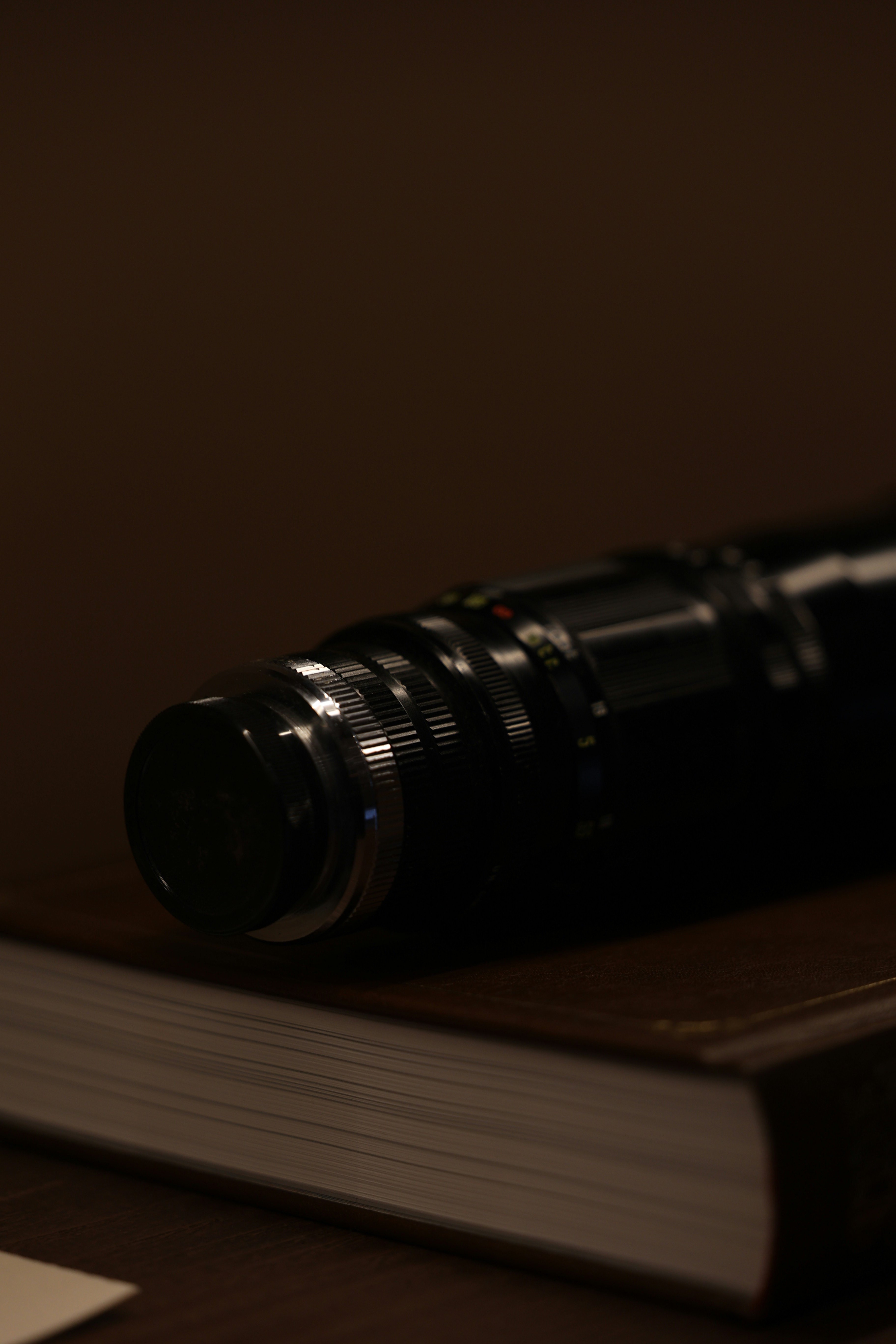 A black camera lens rests on a closed book.