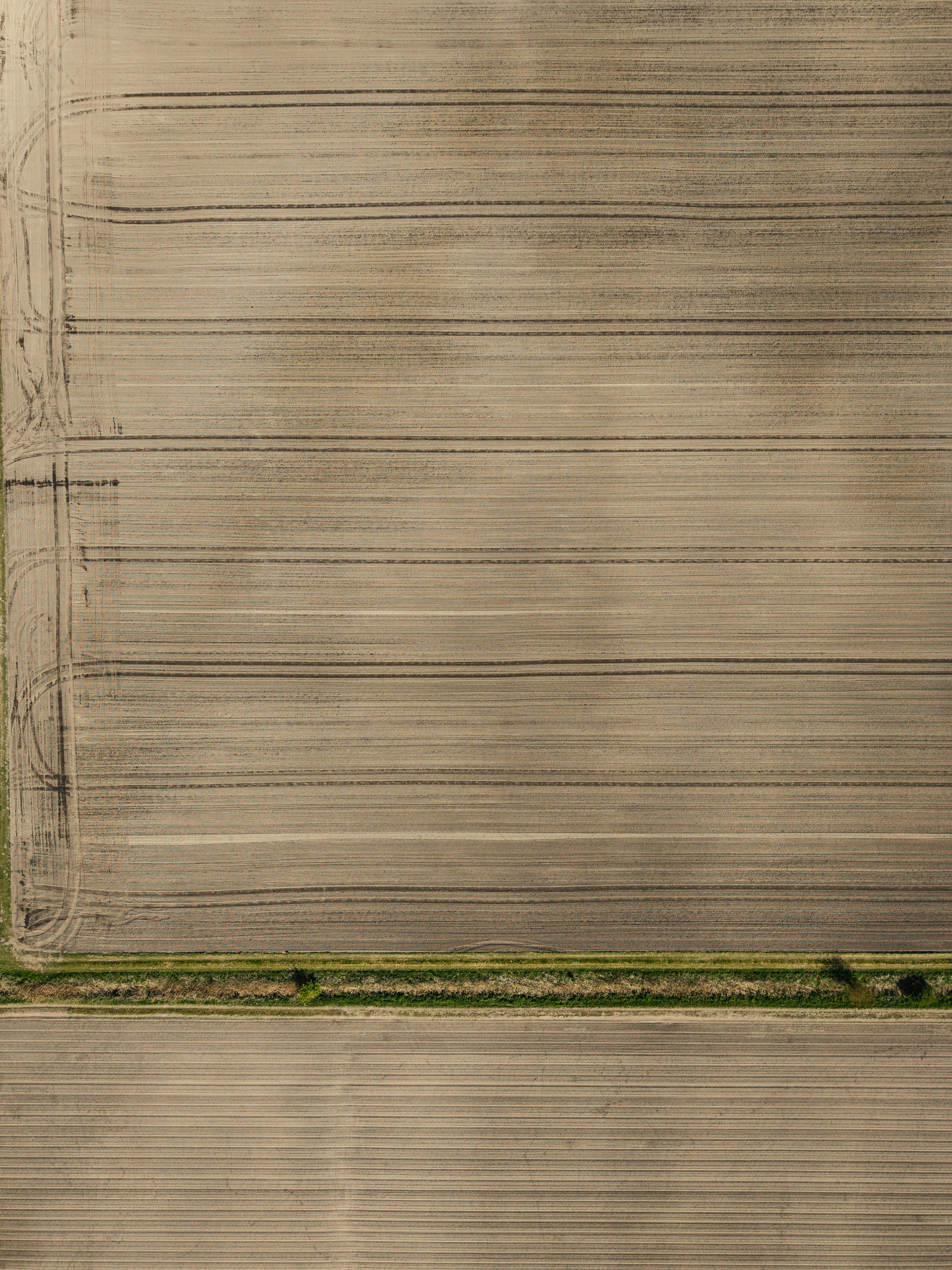 Aerial view of a plowed agricultural field with tire tracks.