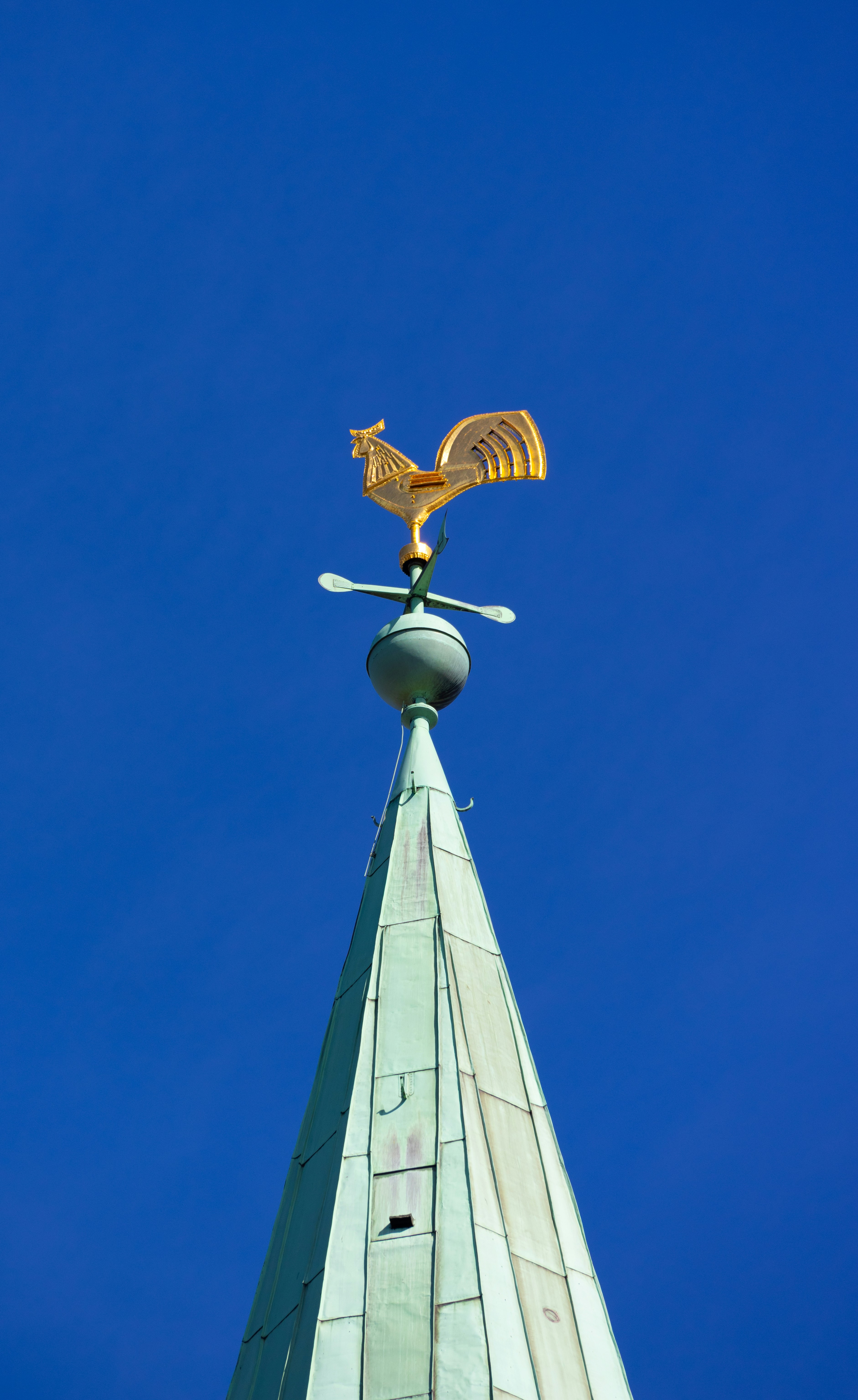 Golden rooster weather vane atop a green spire