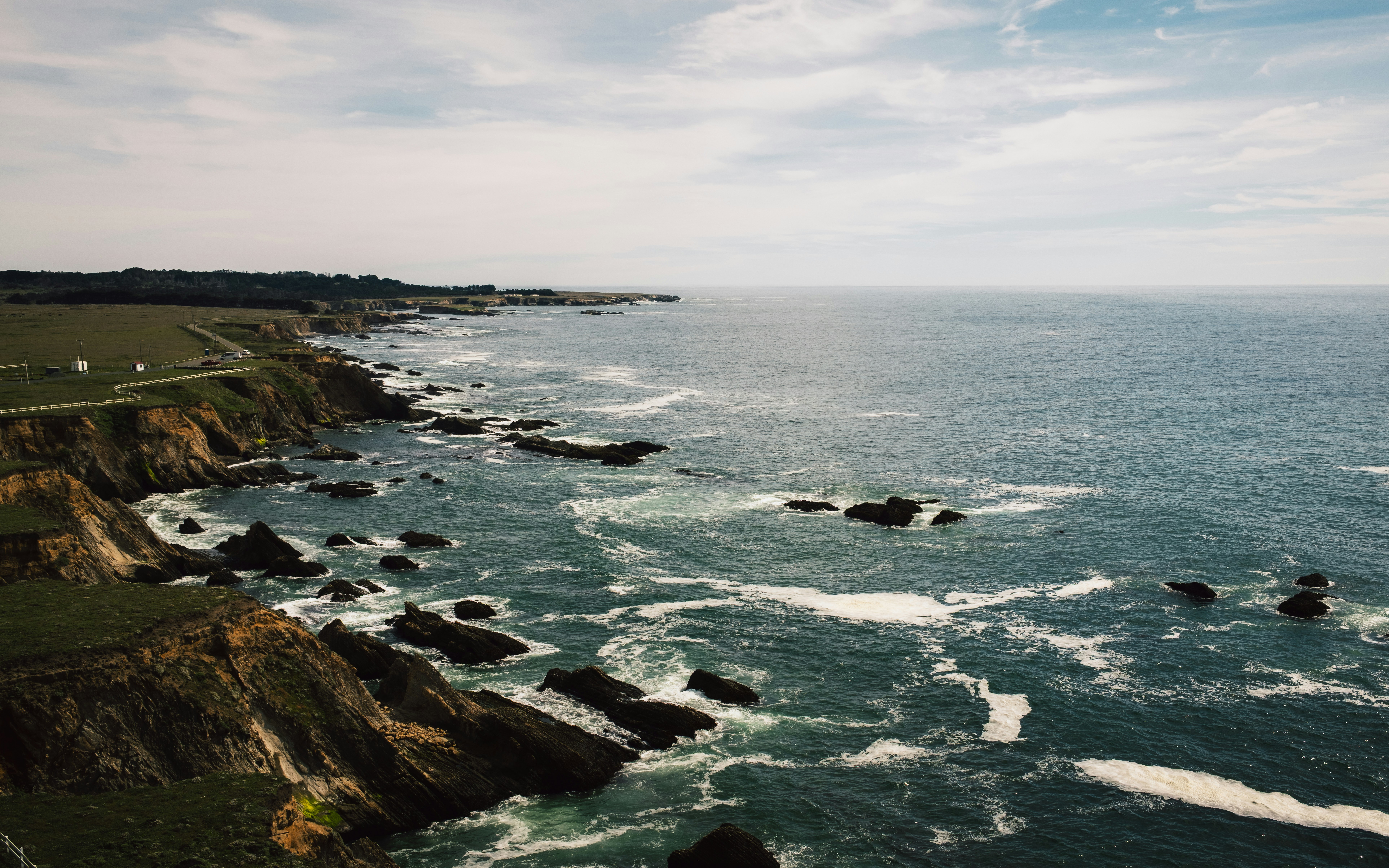 Waves crash against rocky coastline under a cloudy sky