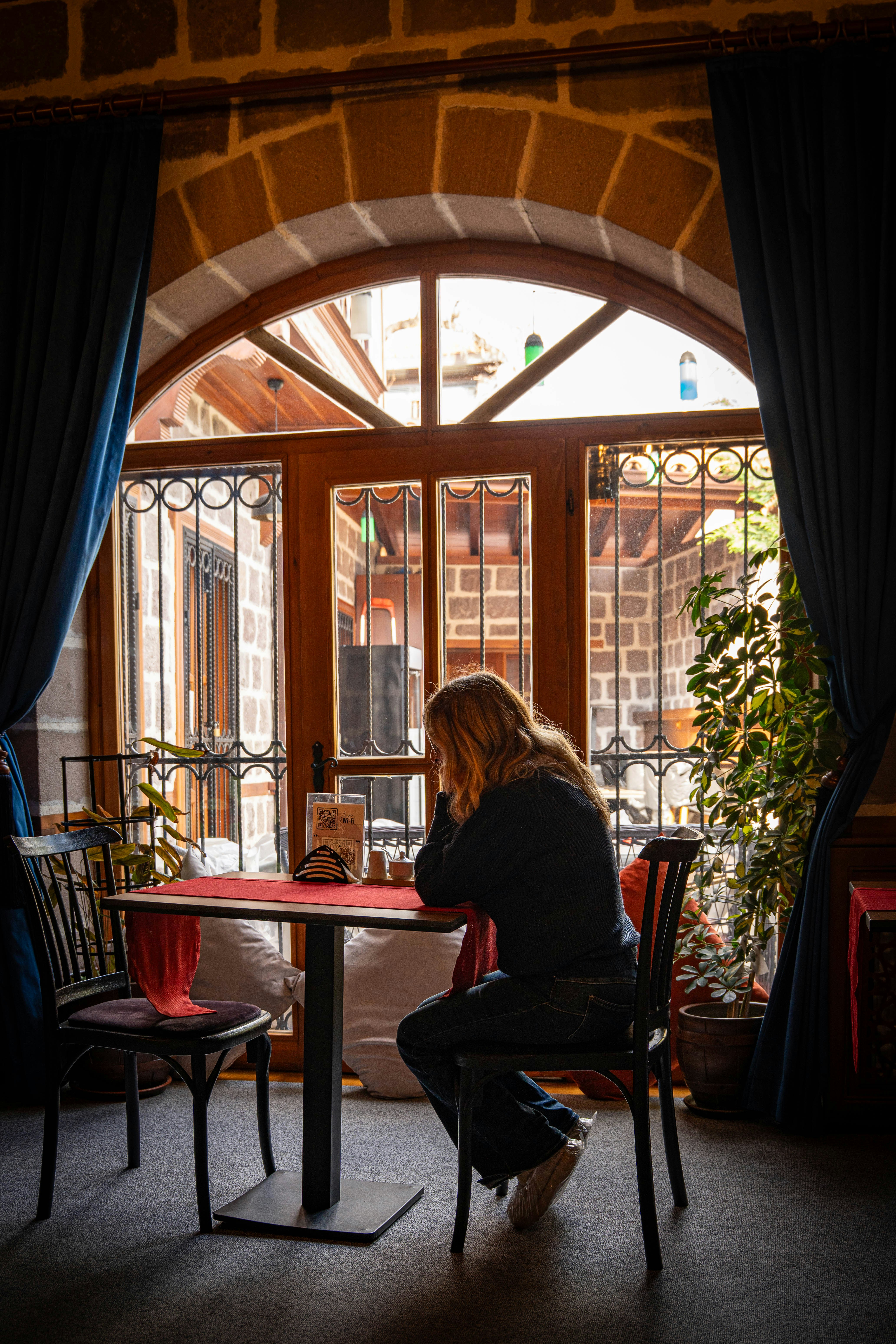 Woman sitting alone by a window in a quiet space, representing personal space, reflection, and rebuilding healthy boundaries.