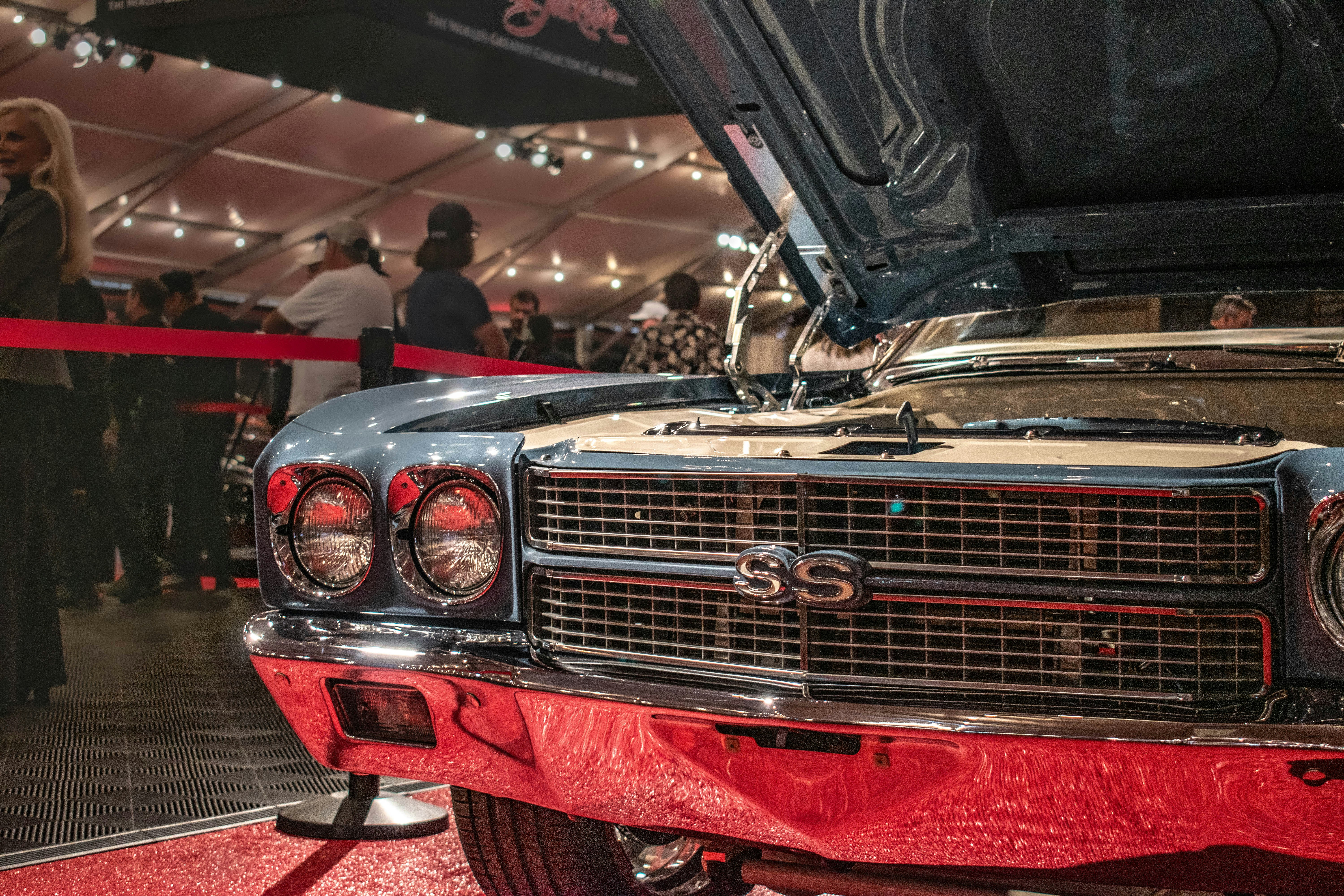 Classic blue car with hood open at an exhibition.