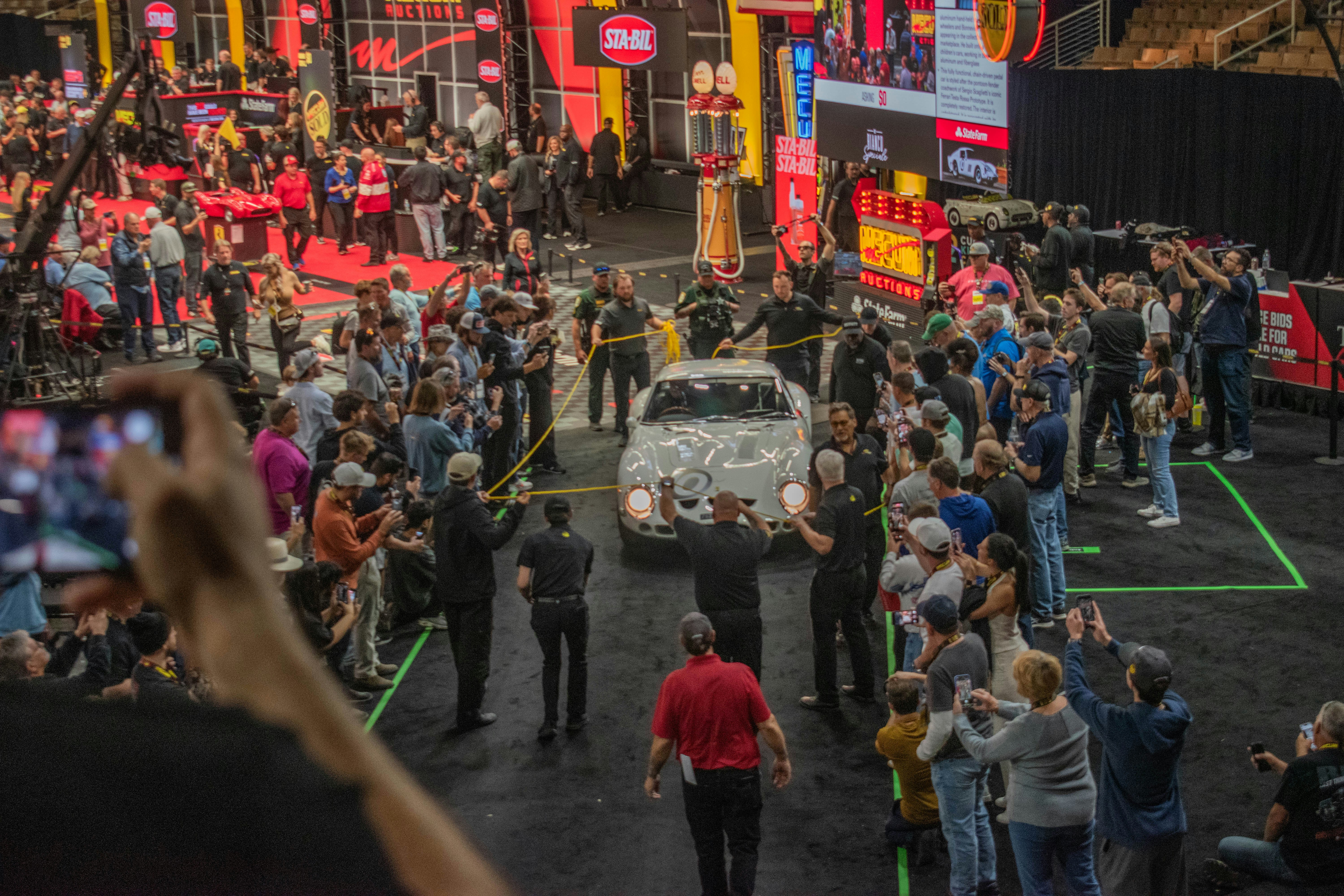 Crowd watches as a car is presented at an auction.