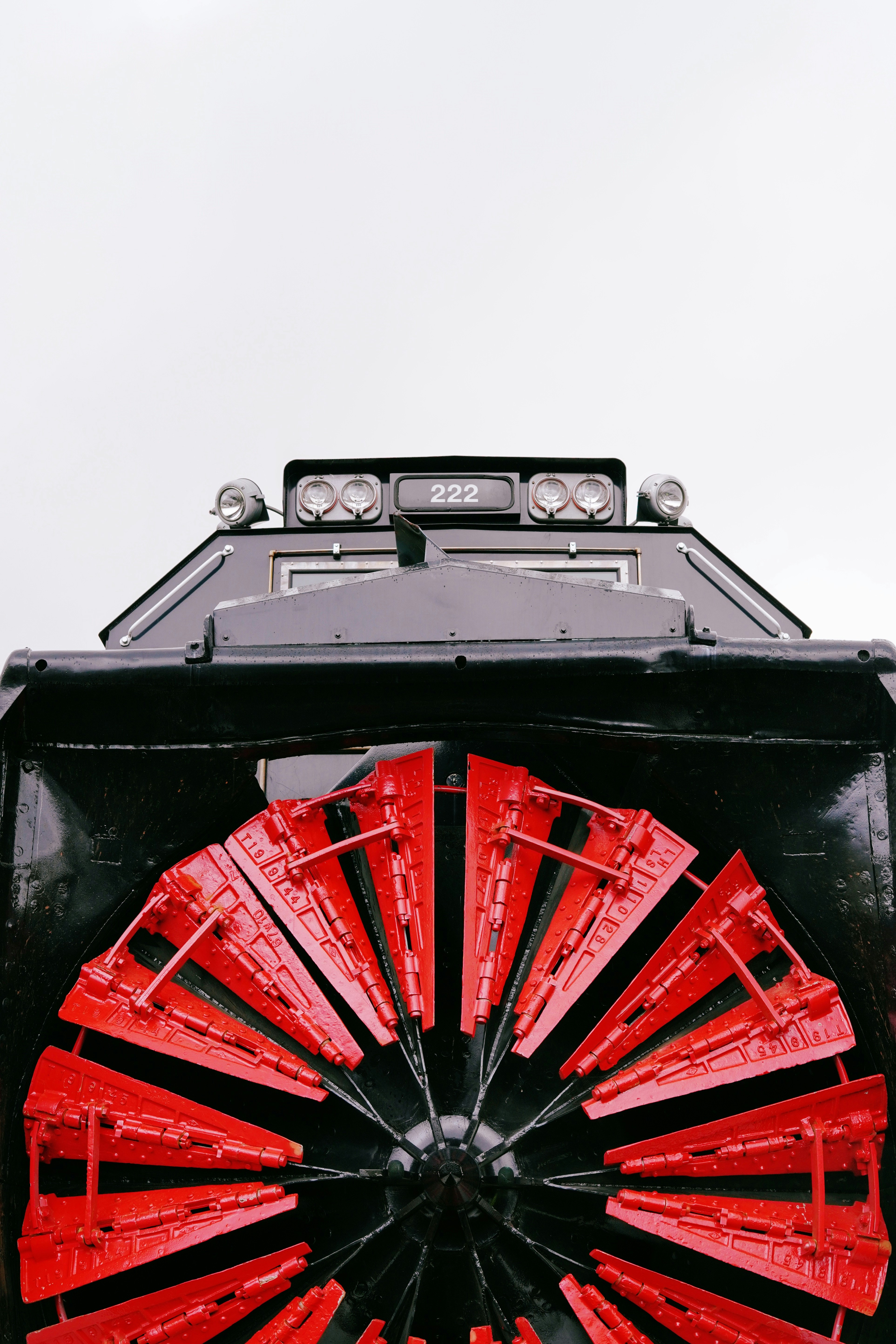 Front view of a black snowplow with red blades