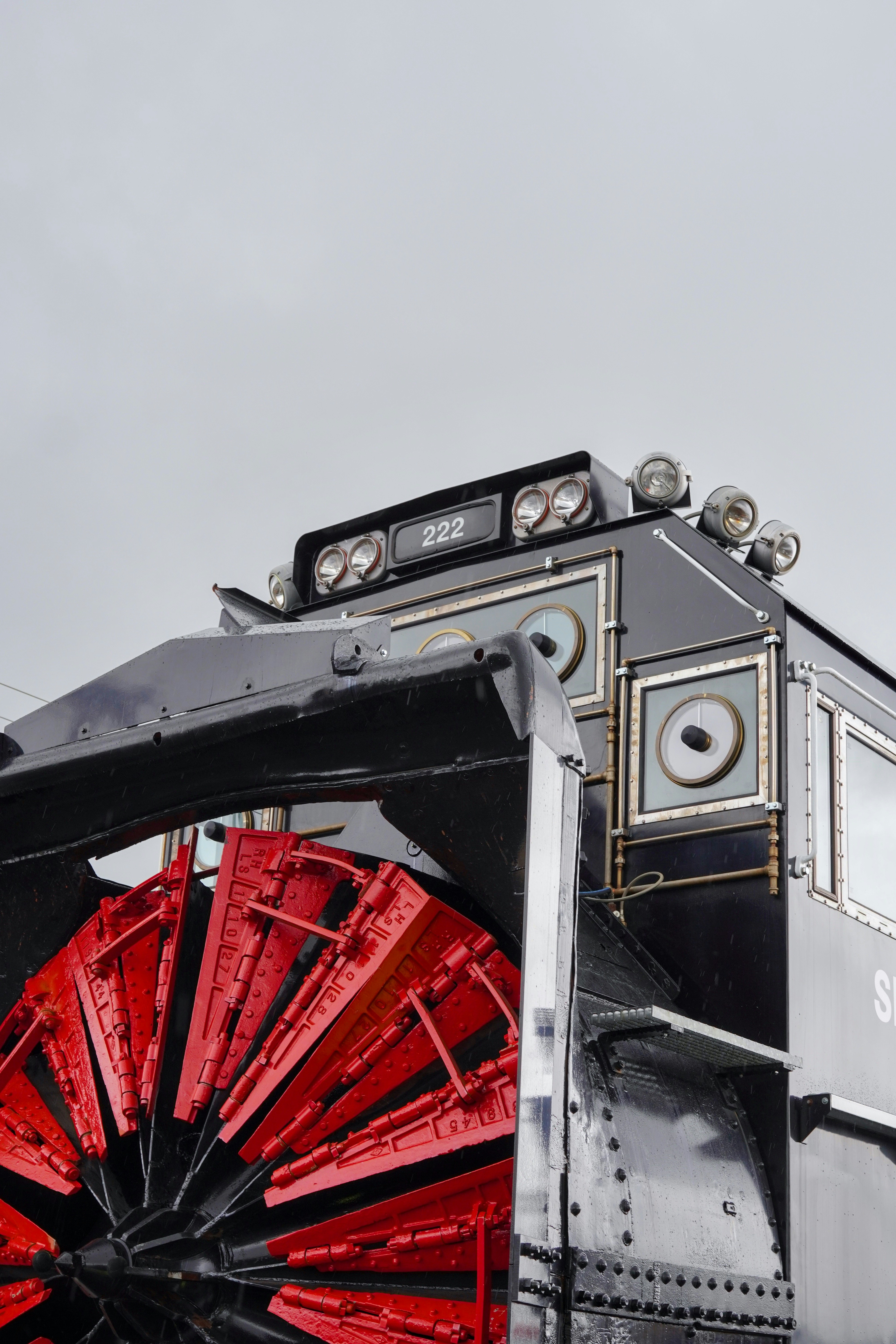 A black snow plow train with a red rotary snowplow.