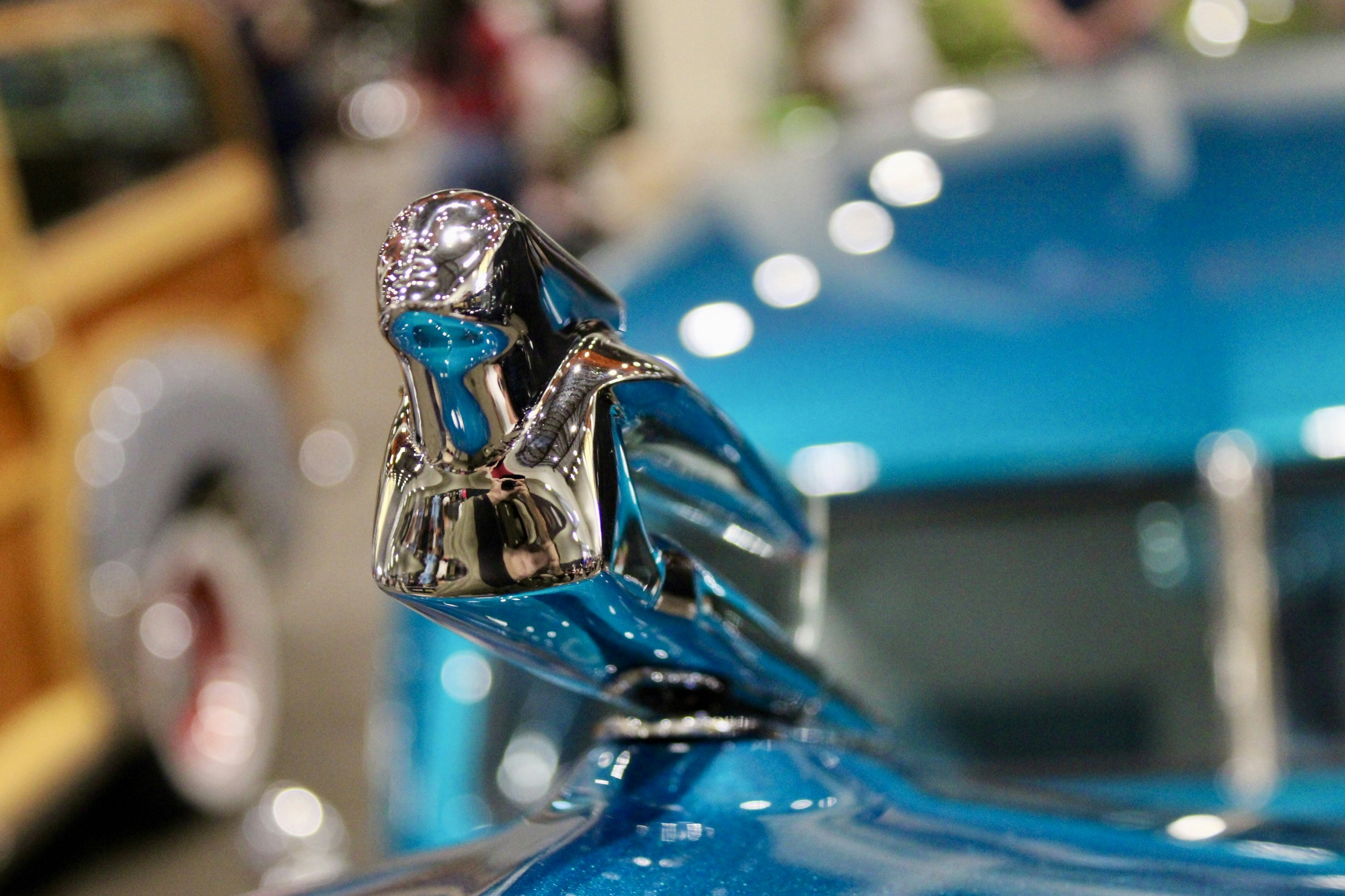 Close-up of a shiny blue car hood ornament.