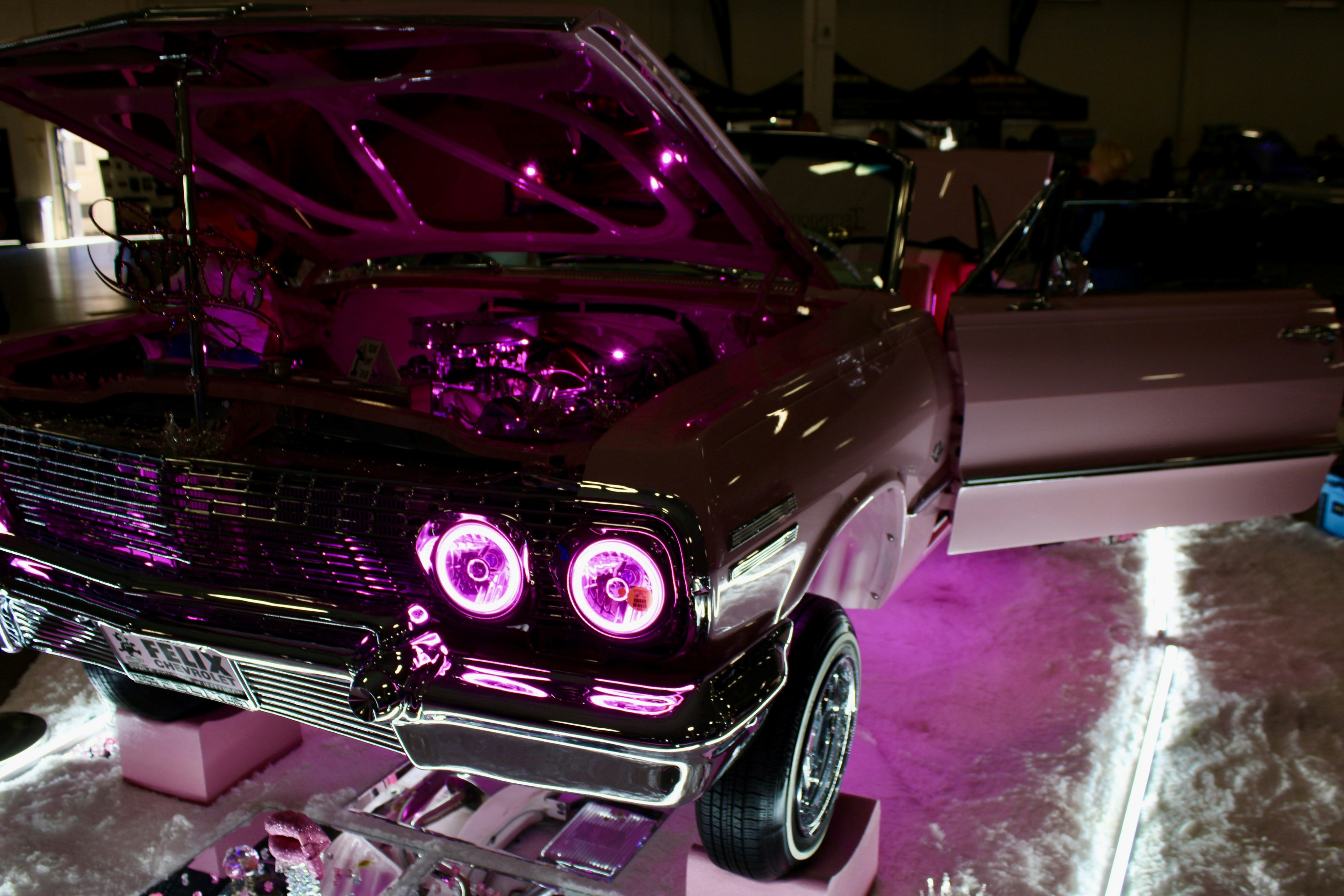 Individuelles Auto mit rosa Neonlichtern und Chromdetails.