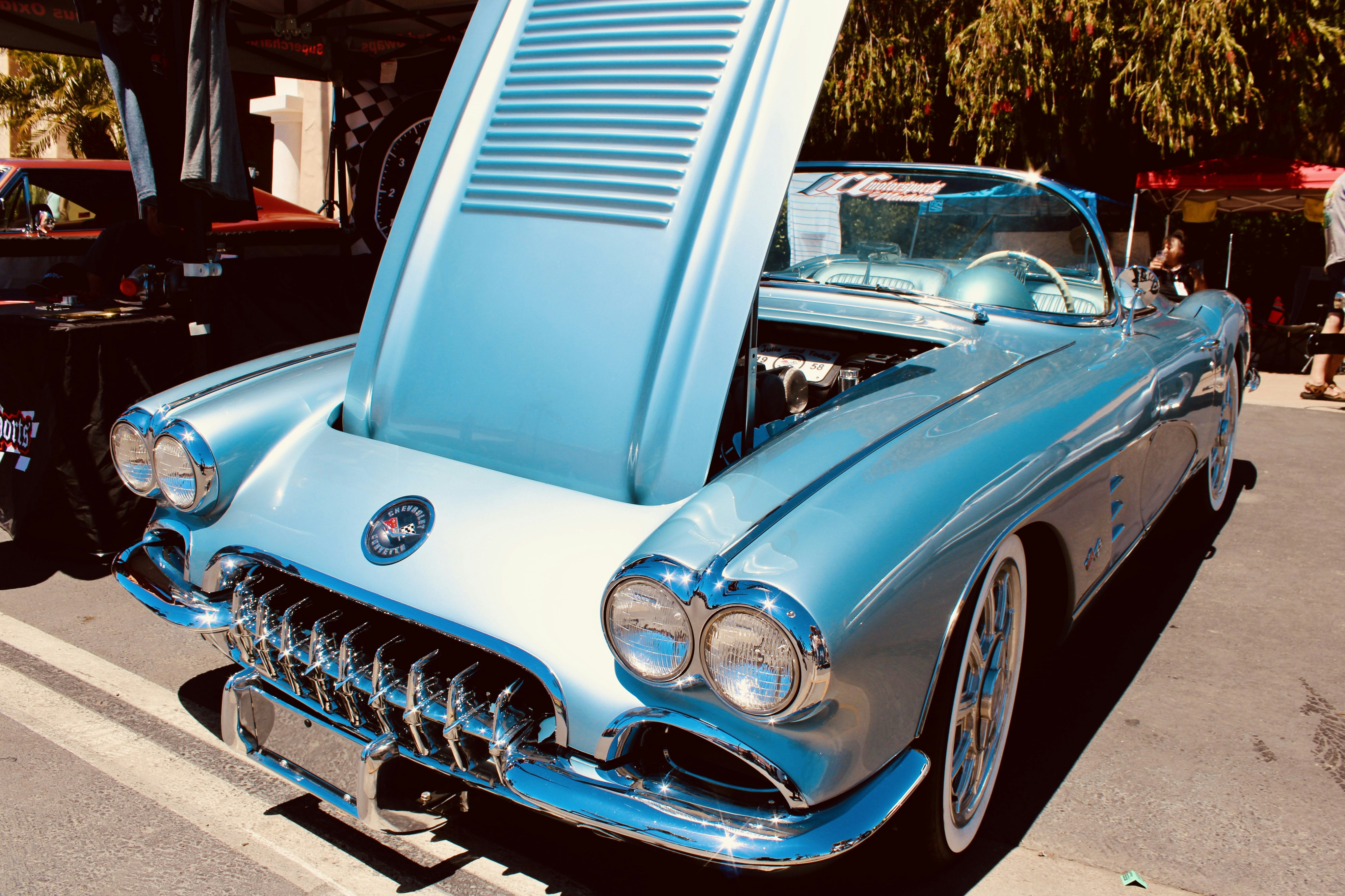 A classic light blue convertible car with hood open.