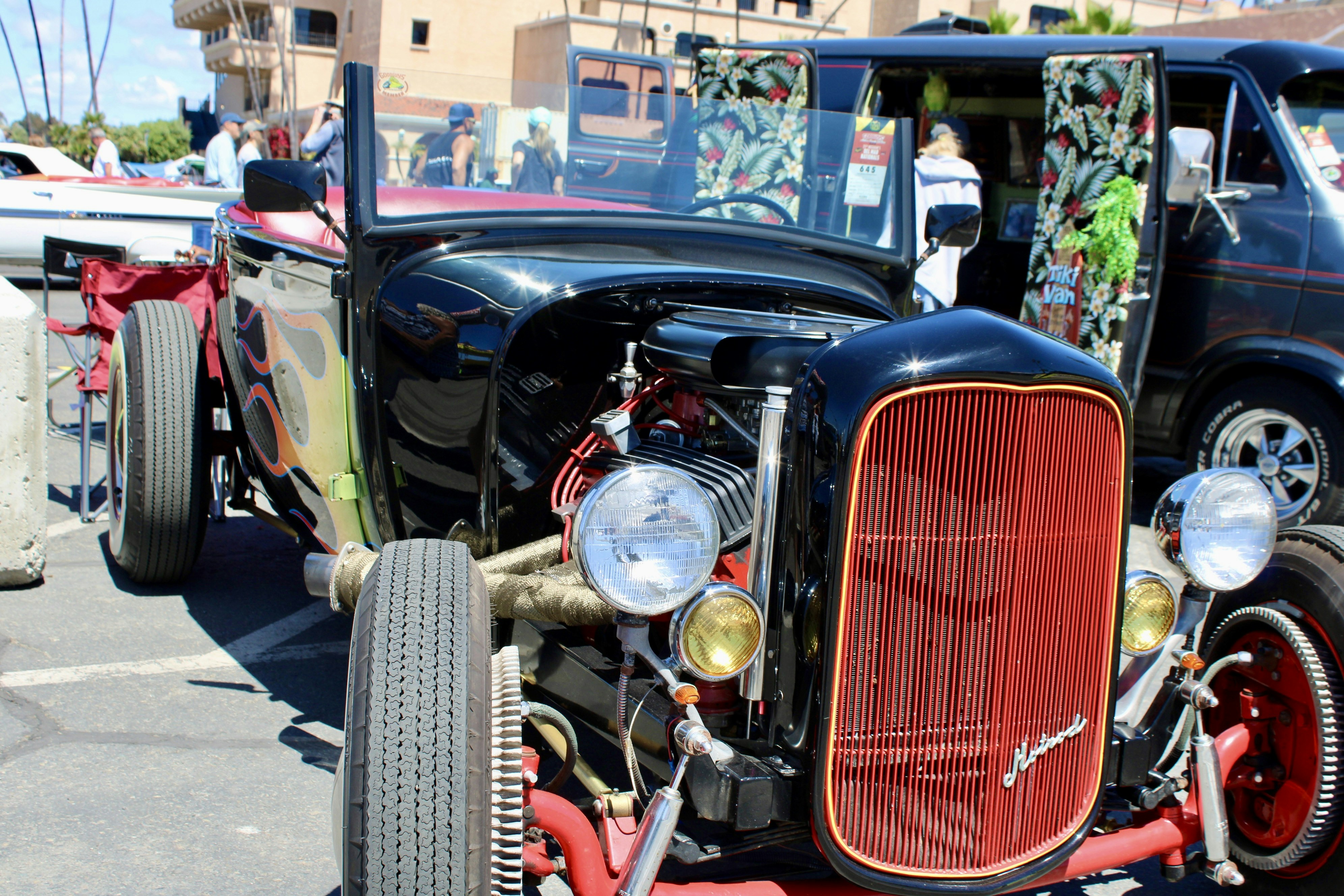 A shiny black hot rod with a red grille