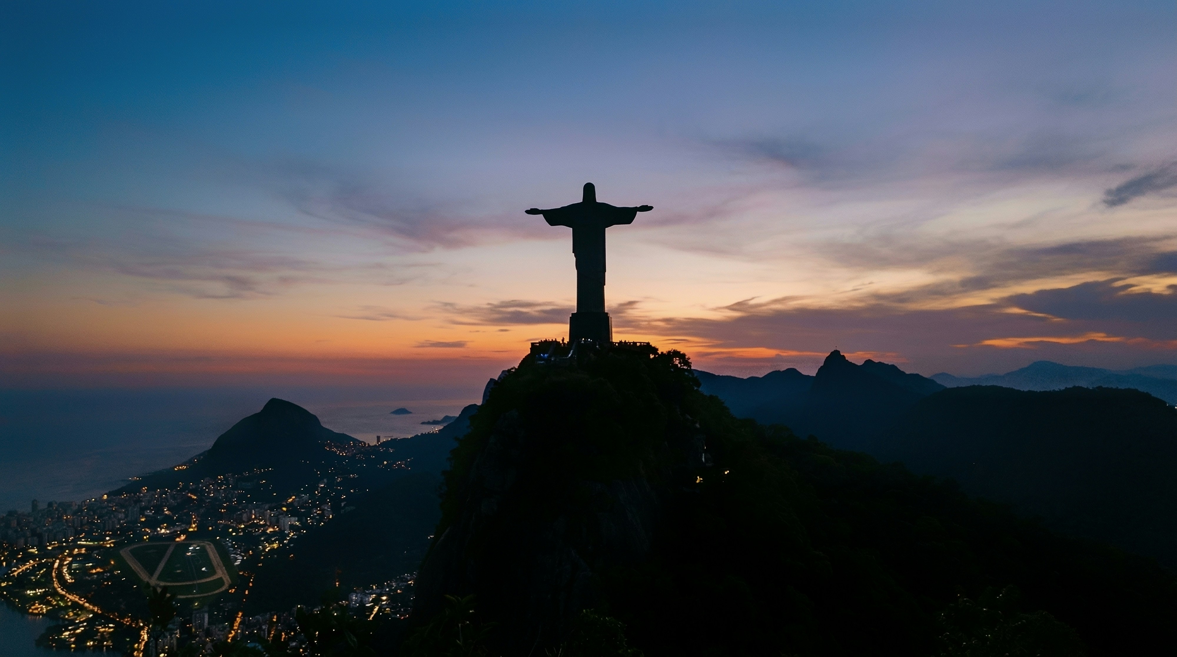 Christ the redeemer statue overlooking rio de janeiro at sunset
