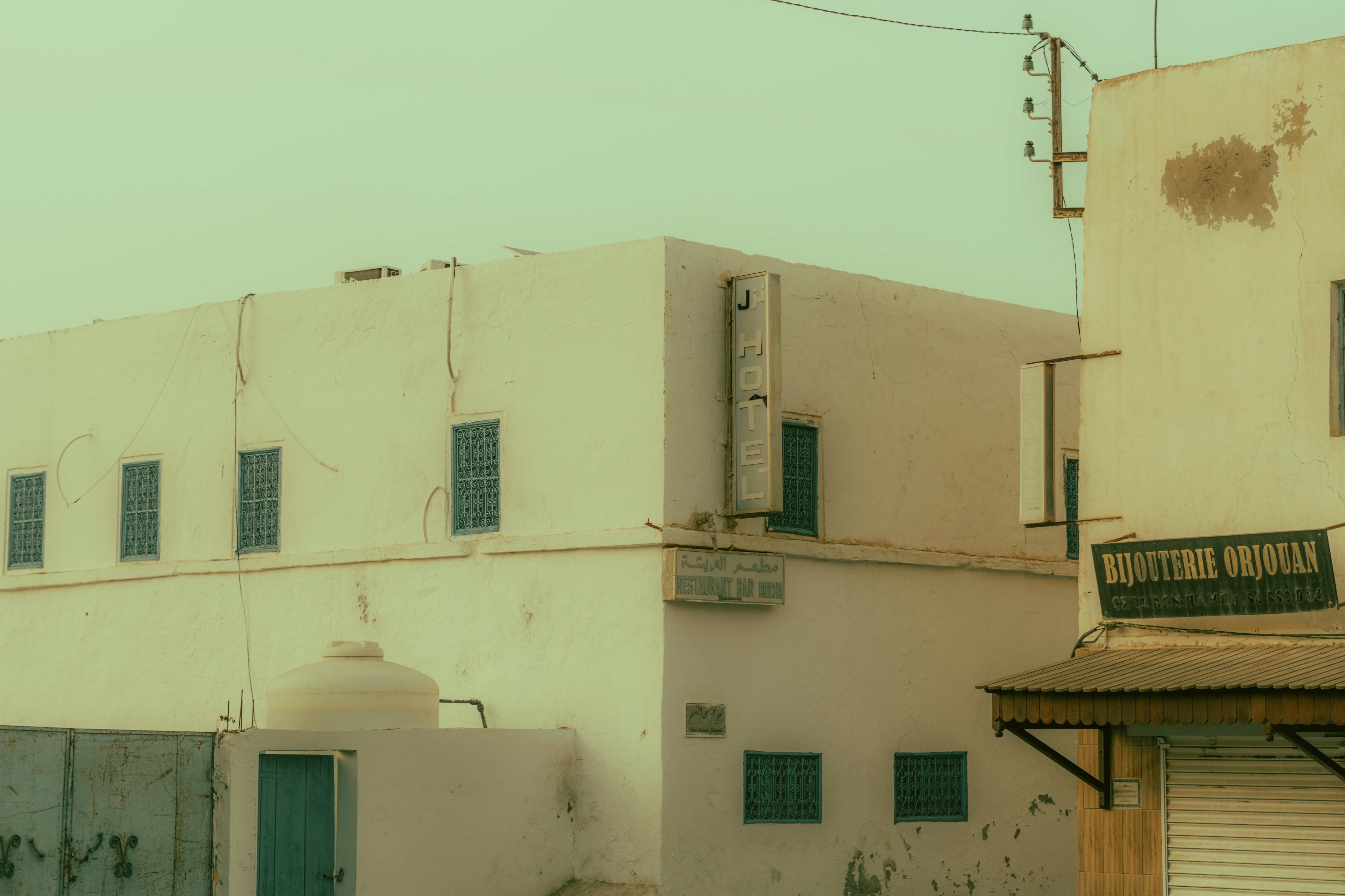 White buildings with blue windows under a hazy sky.
