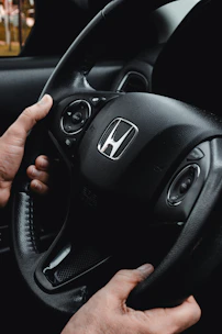 Hands gripping a honda steering wheel inside a car.