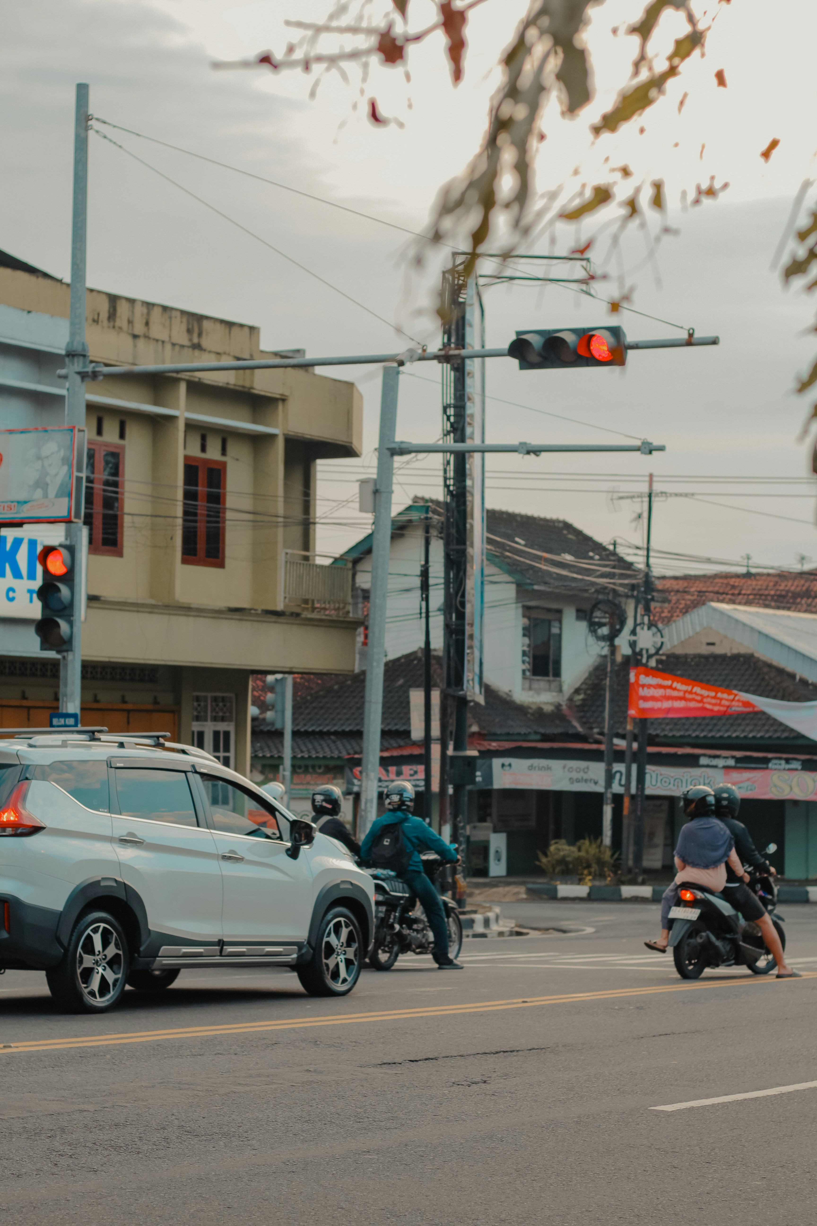 Cars and motorcycles at a traffic light intersection.