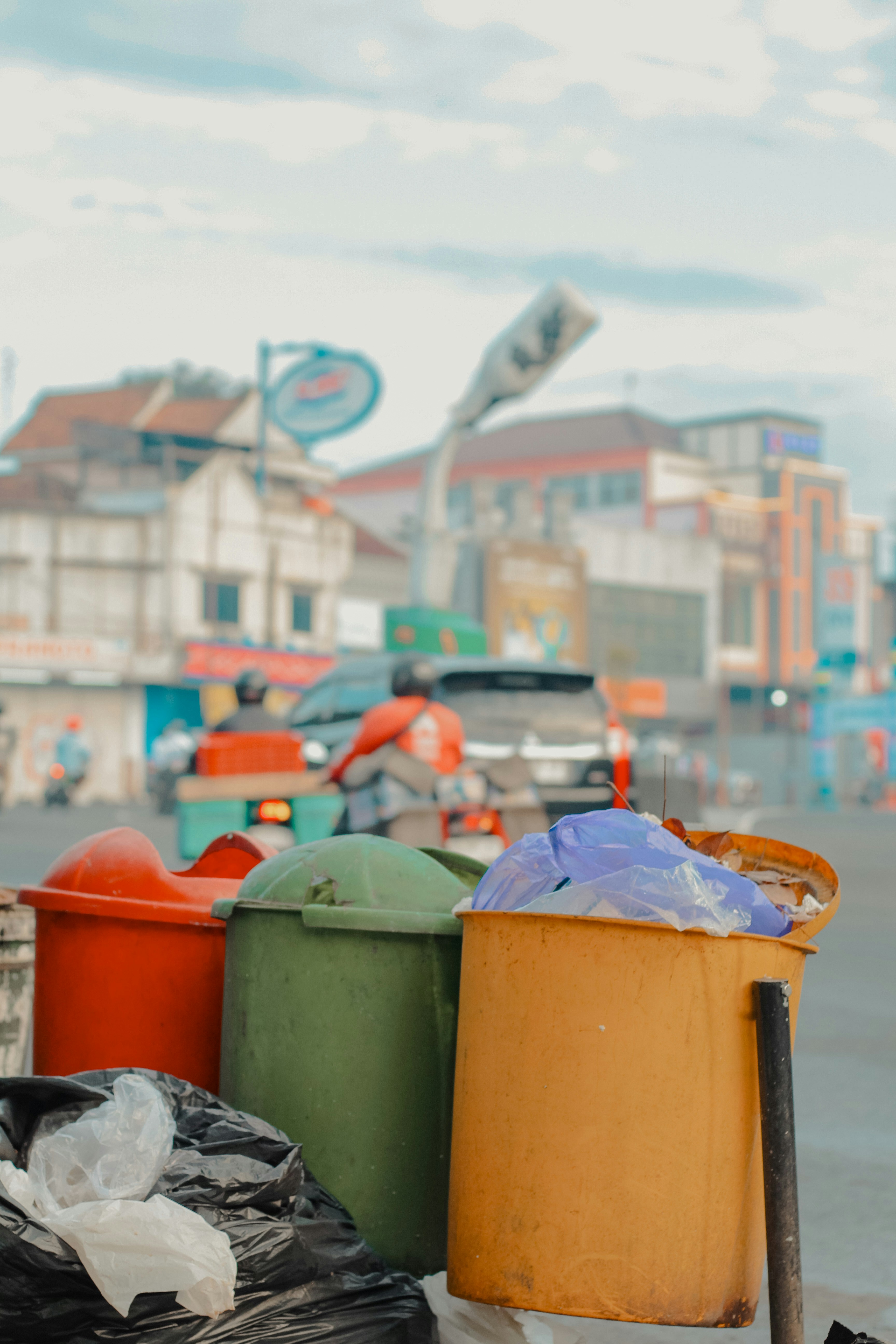 Three colorful trash bins on a street