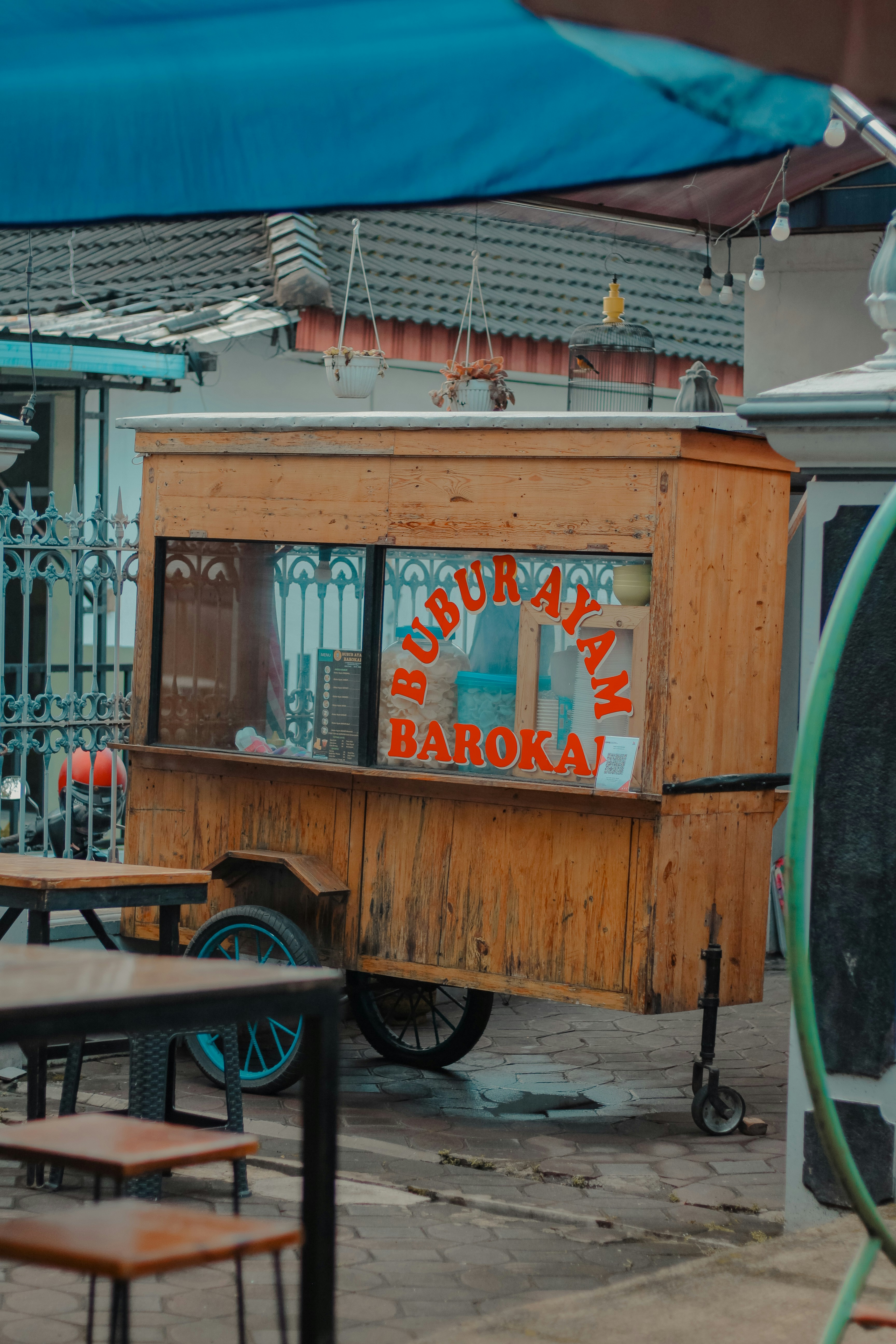 Carrito de comida de madera con el cartel de "bubur ayam baroka"