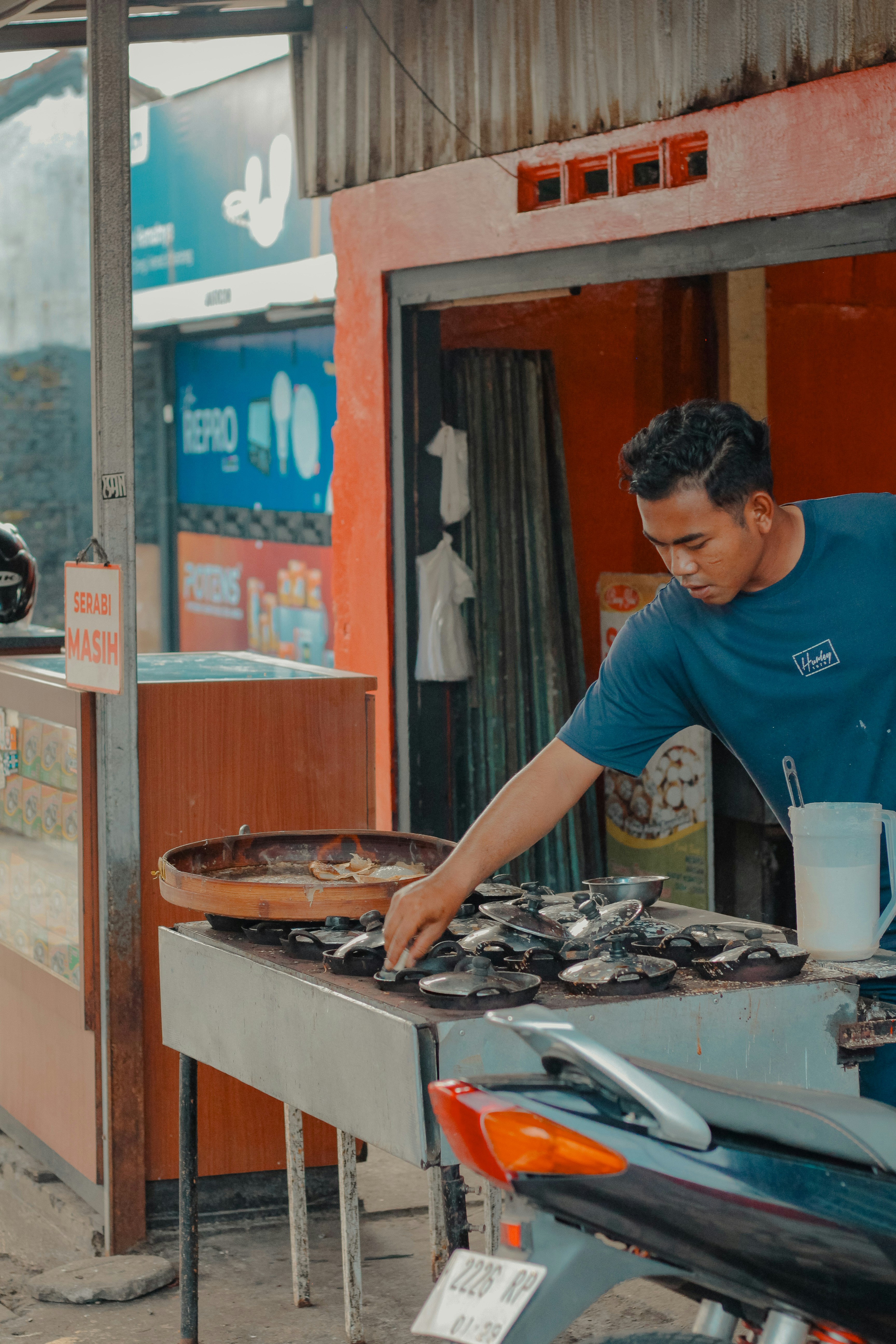 Pria memanggang ikan di kios luar ruangan