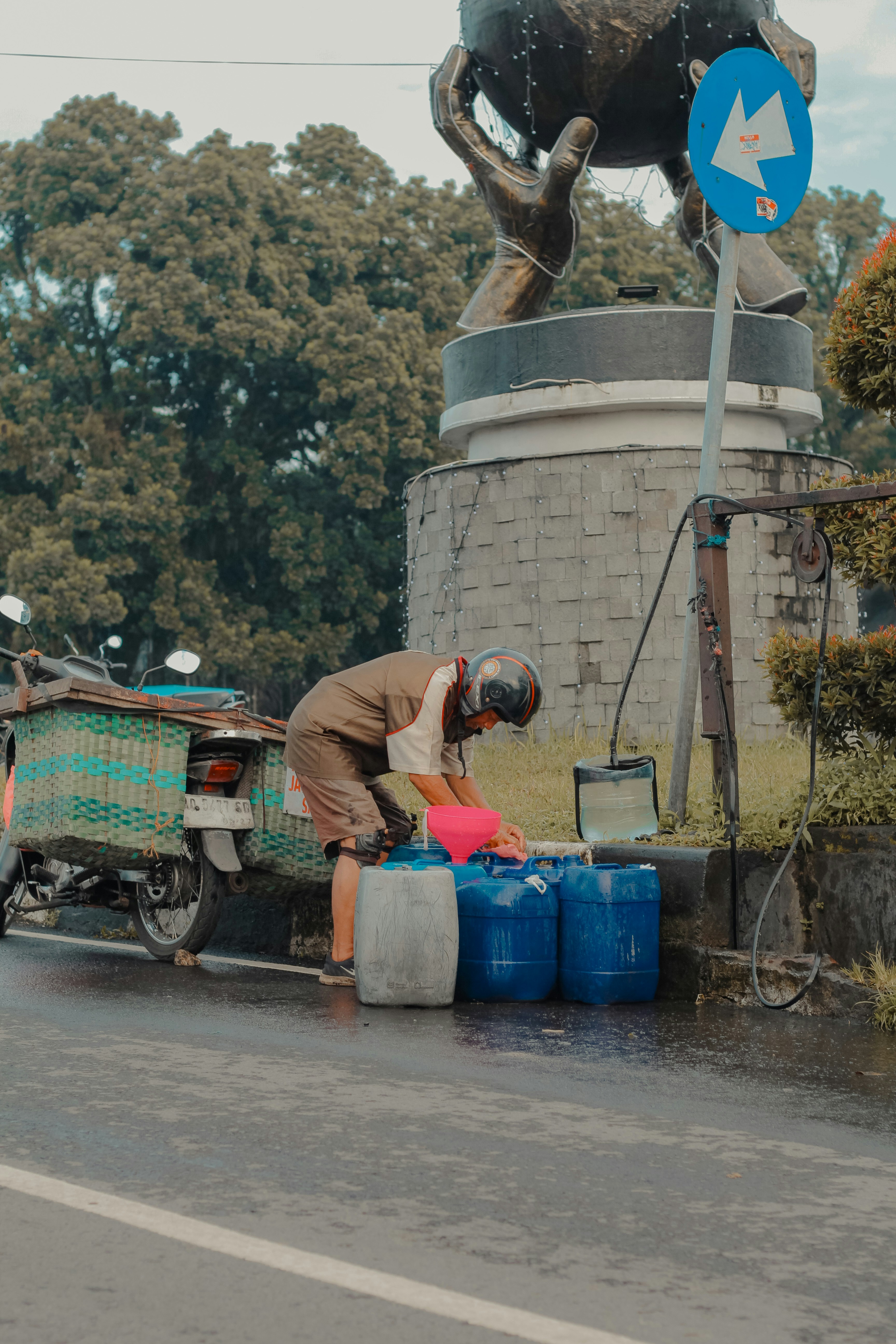 Man filling blue barrels from a motorcycle