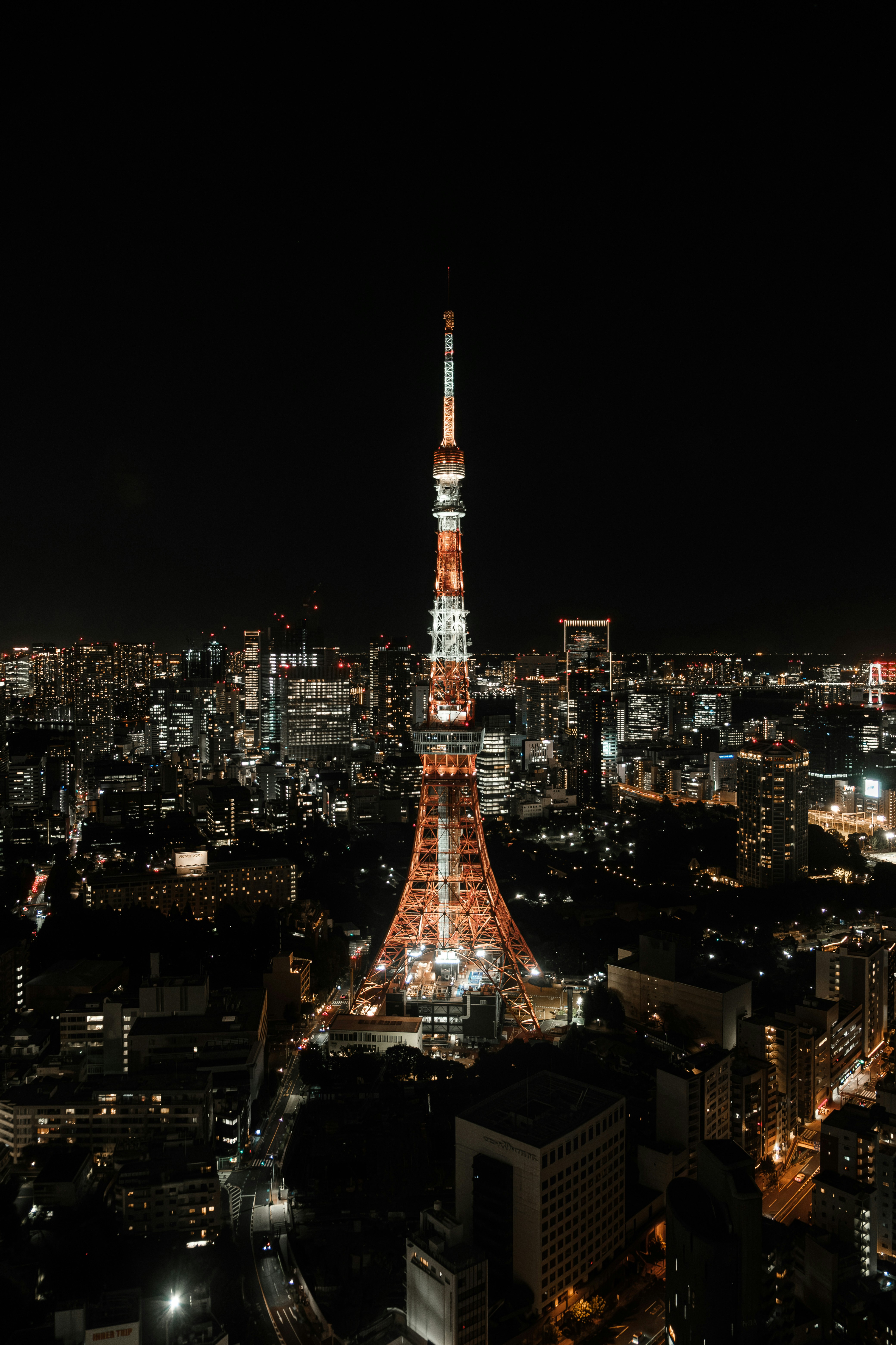 A torre de Tóquio ilumina uma paisagem urbana extensa à noite.