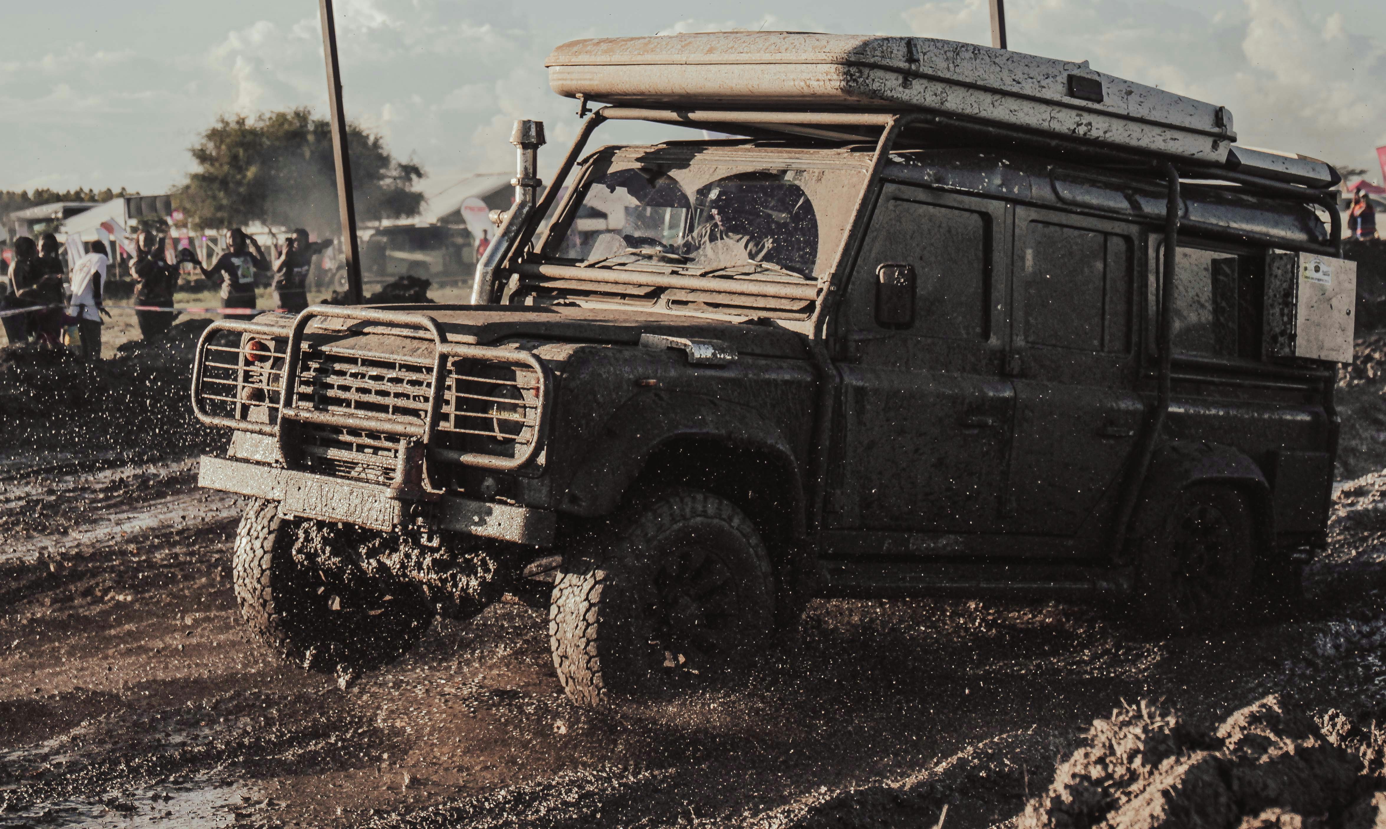 A rugged off-road vehicle driving through muddy terrain.