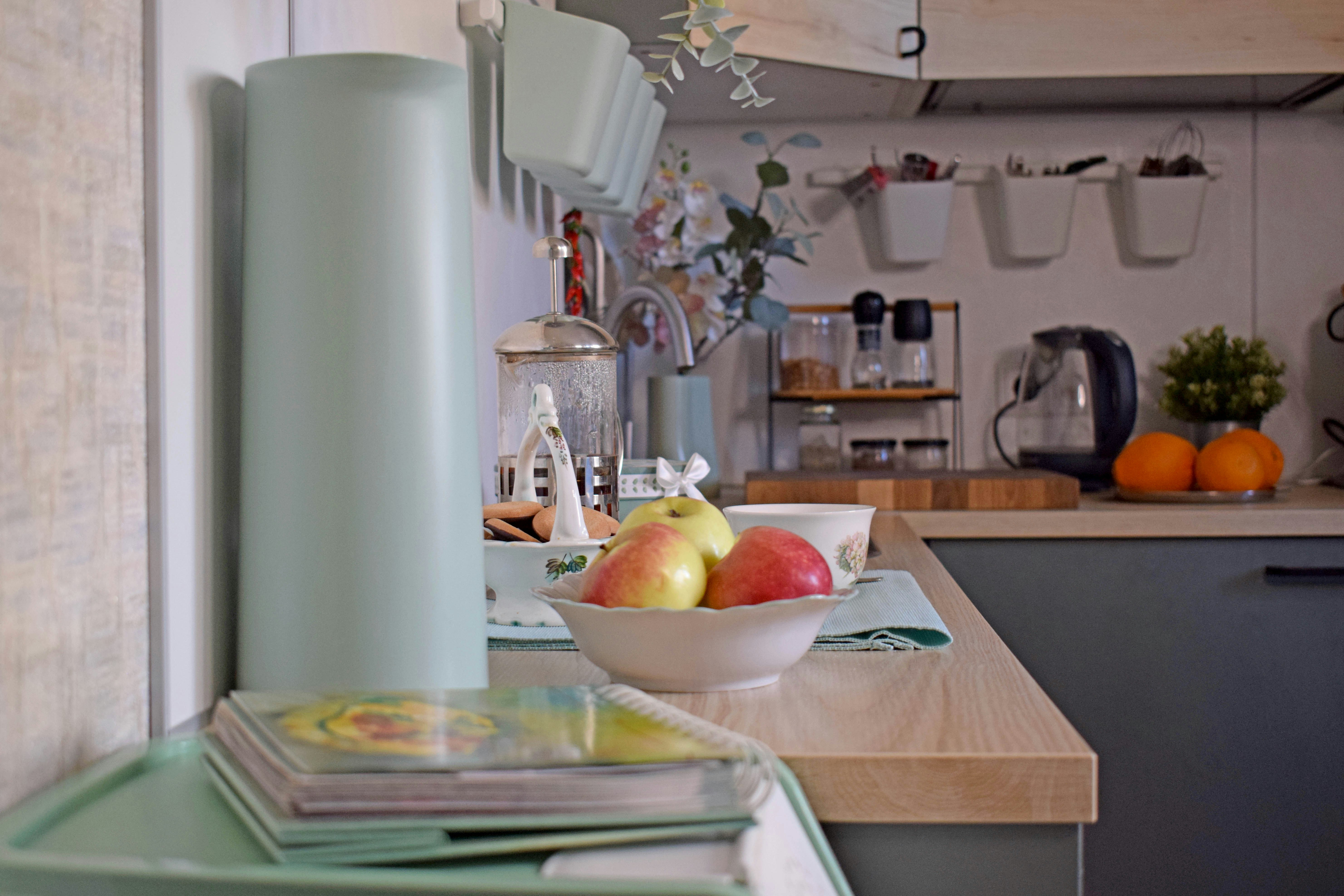 A light blue kitchen counter with fruit and magazines.